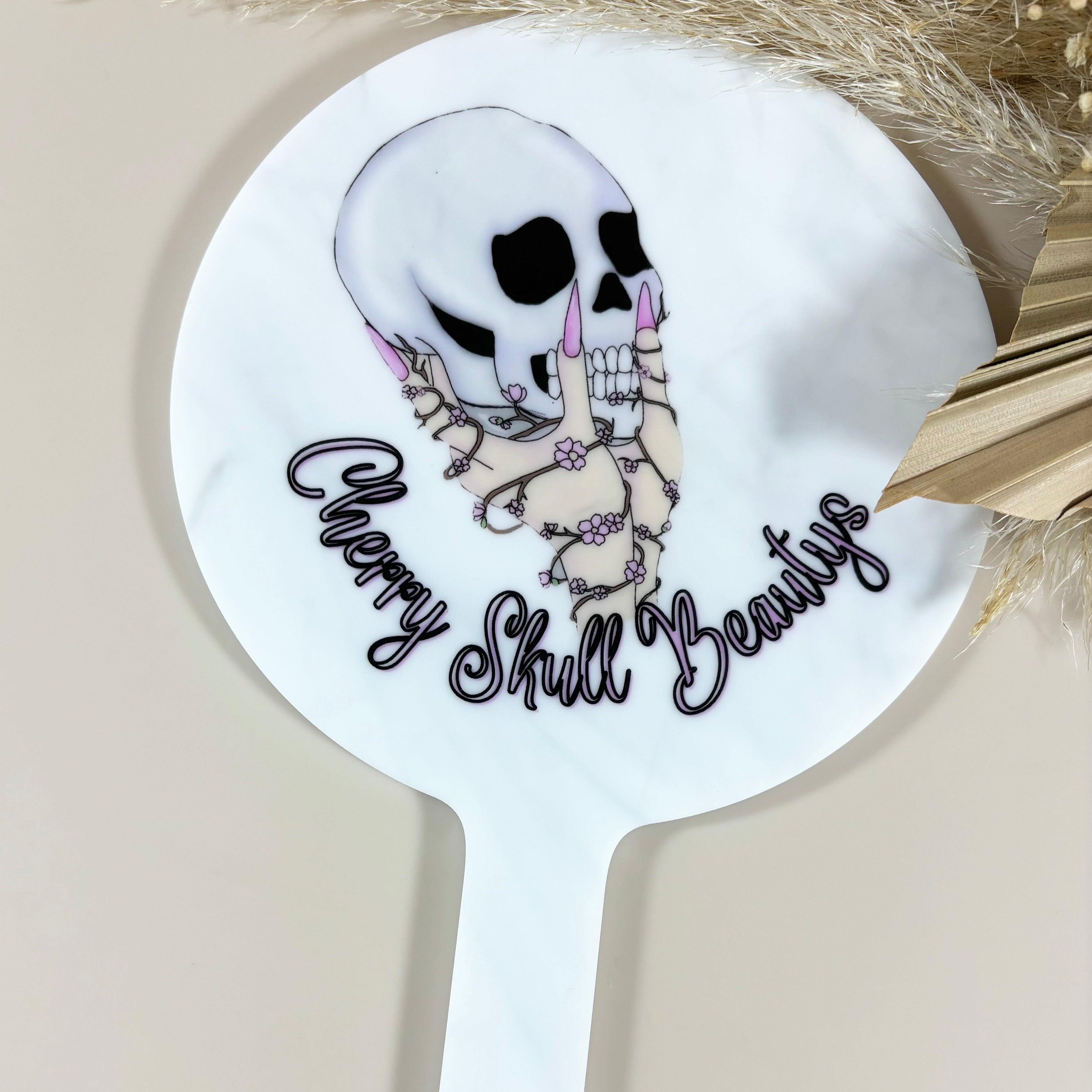 White round handheld mirror with edgy skull and sunglasses design