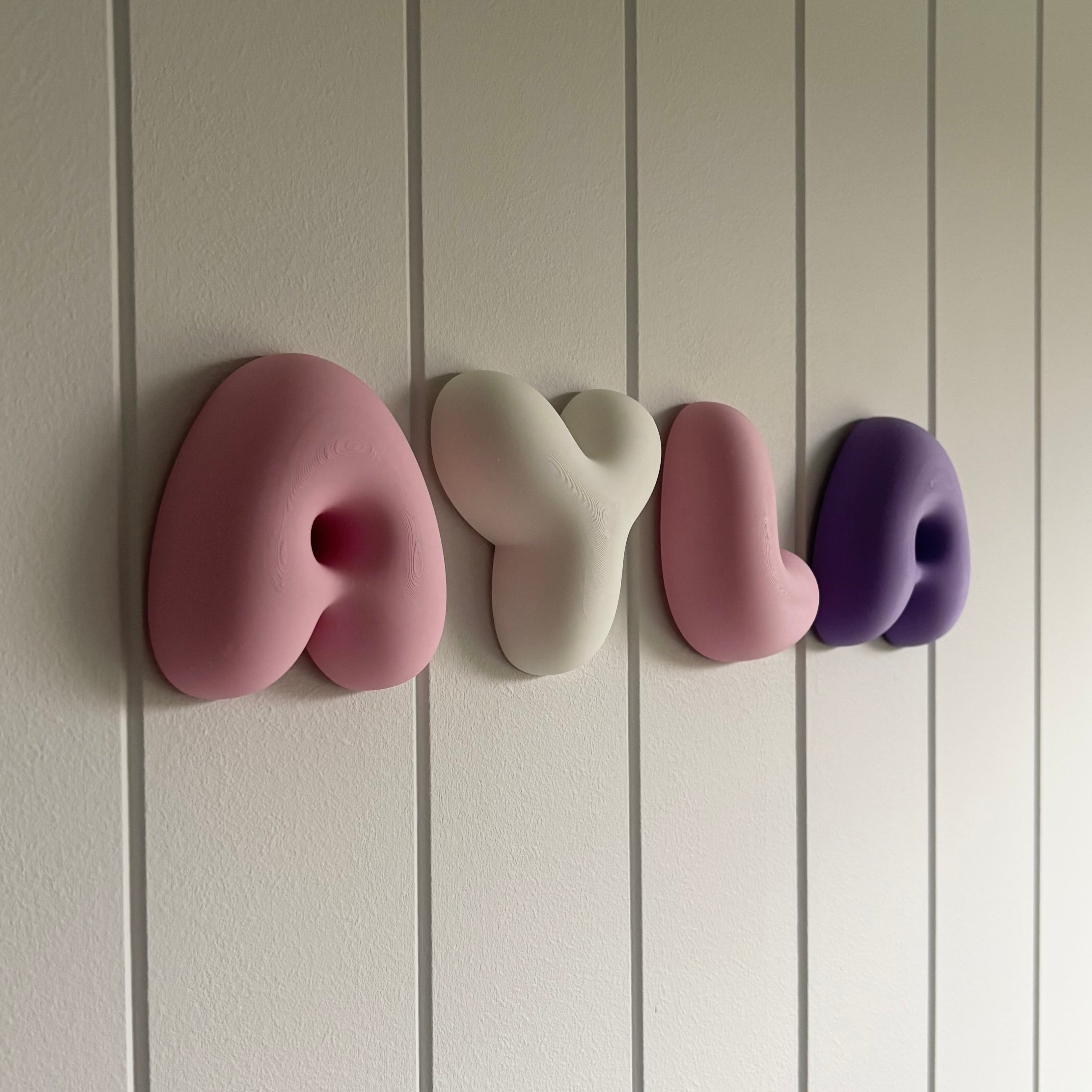 Personalised bubble name letters in pink, white and purple 3D printed PLA mounted on a wall for nursery and kids bedroom décor.