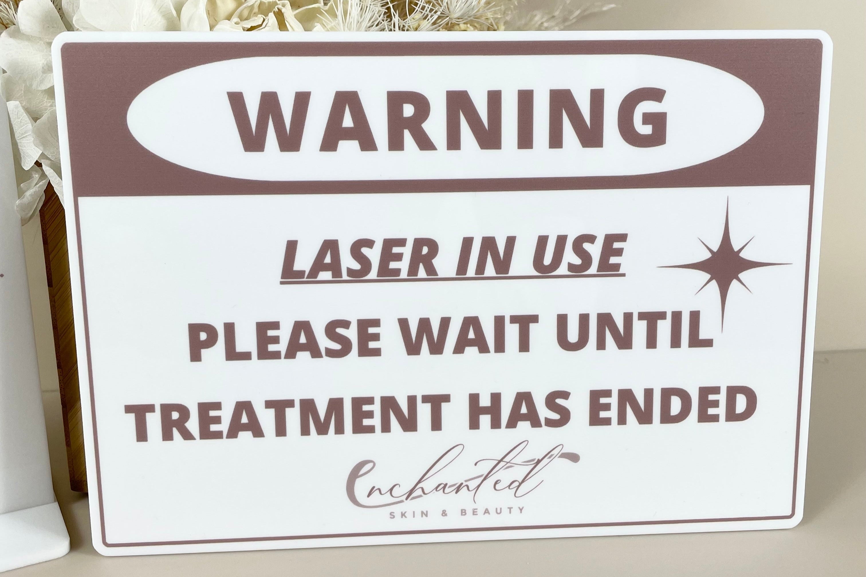 White laser in use warning sign with brown text and salon logo for treatment room door.