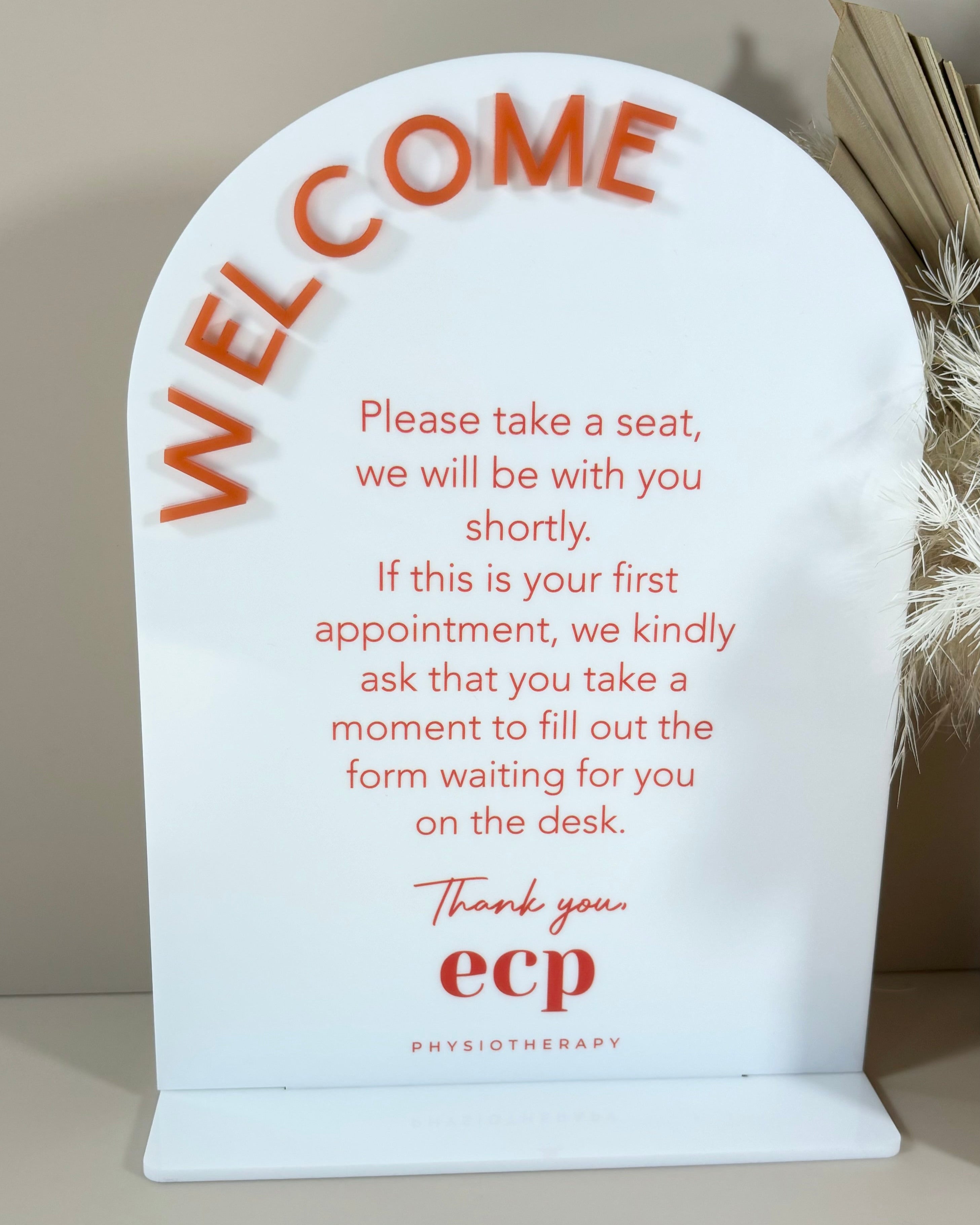 White acrylic welcome message sign with red text for reception areas