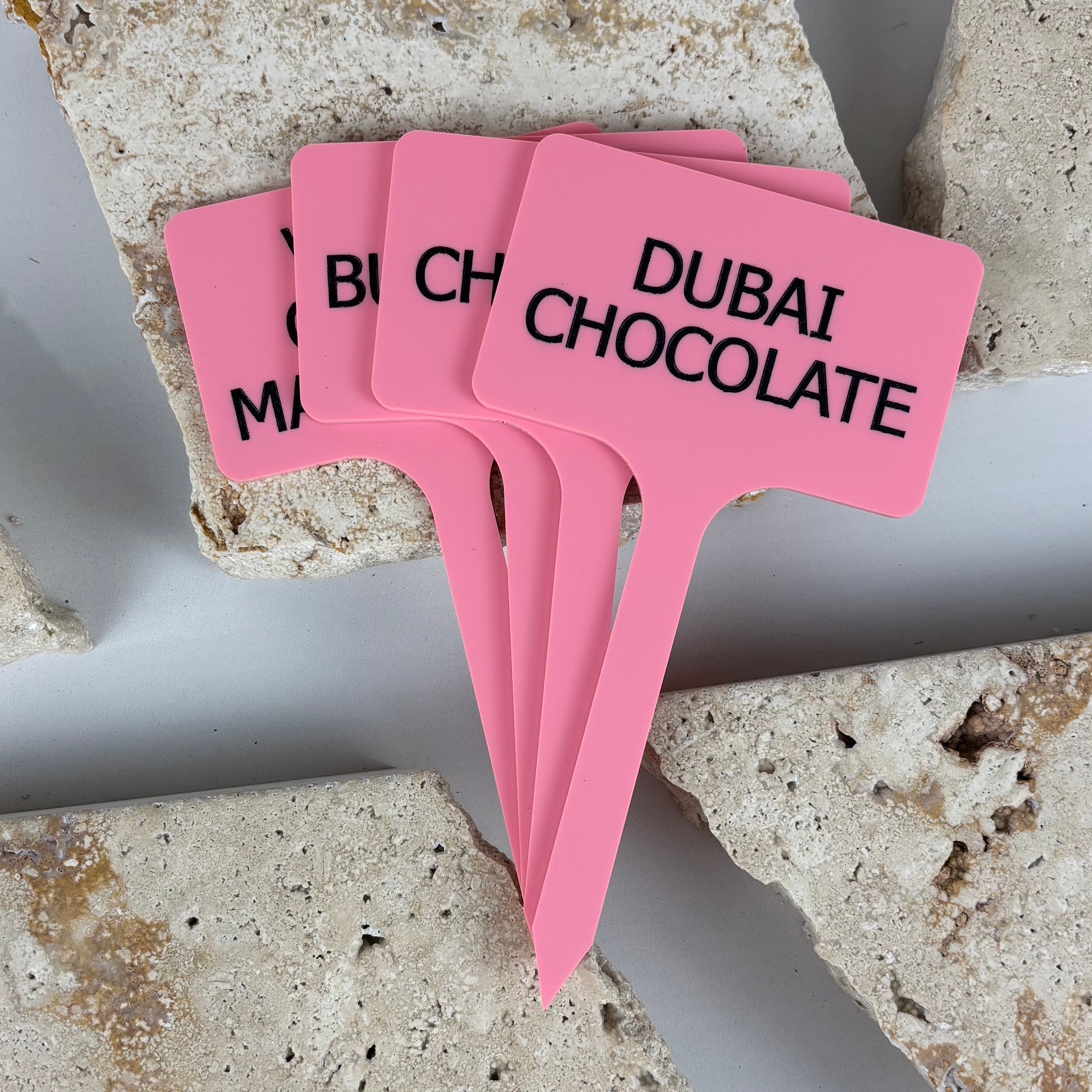 Pink acrylic ice cream flavour paddles with raised black text