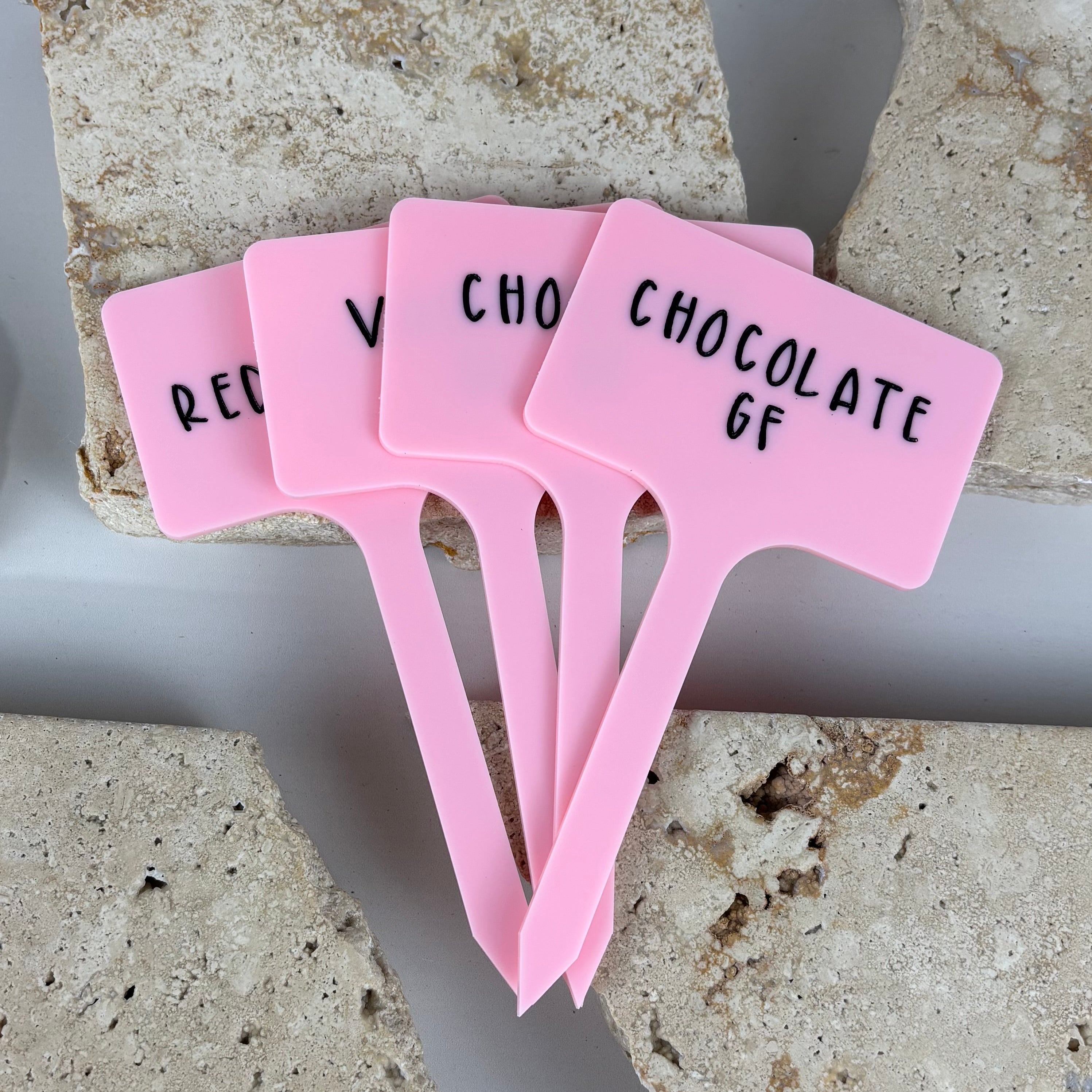 Personalised acrylic ice cream sticks in pink with raised black text, custom flavour labels for ice cream shops, gelato bars, dessert catering and gluten free menu displays