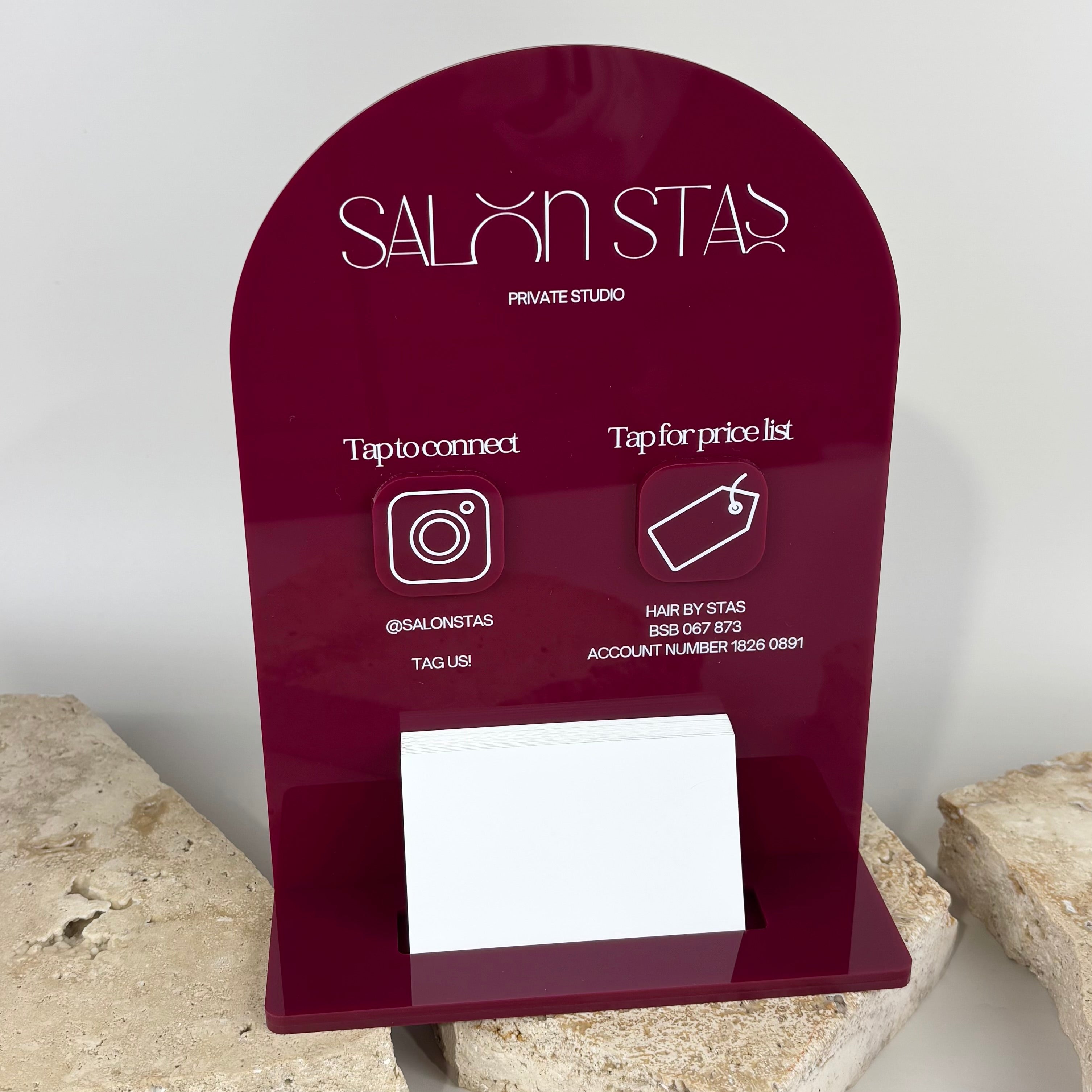 Custom burgundy acrylic NFC business display stand for Salon Stas private studio, featuring tap to connect Instagram icon, tap for price list payment tag, and built-in business card holder, styled on stone backdrop.