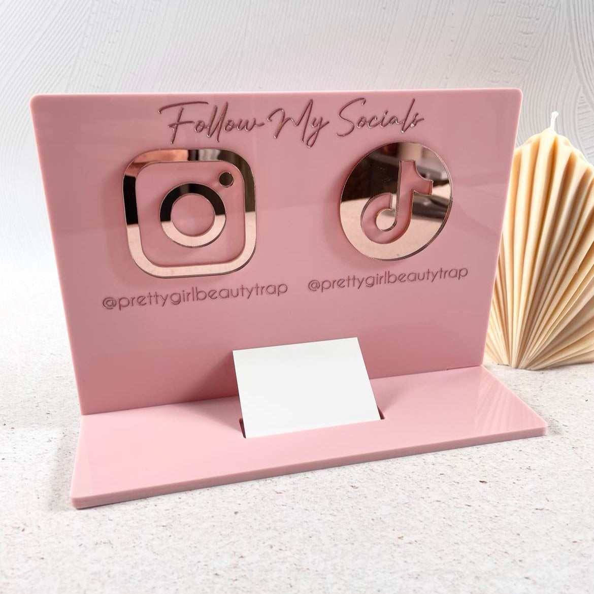Light pink acrylic business card holder with social icons and follow prompt