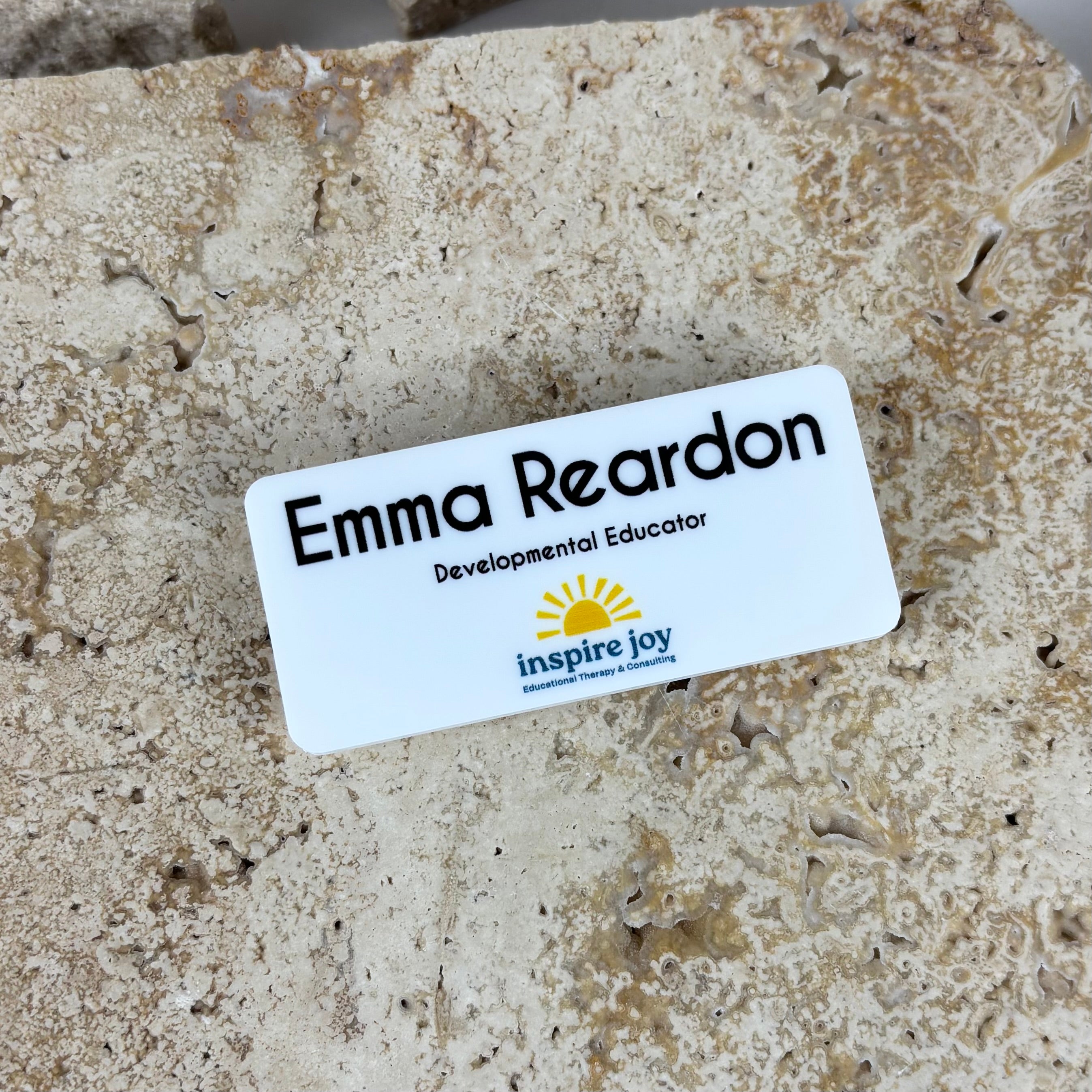 Custom white acrylic name badge with black text and full colour logo for developmental educator