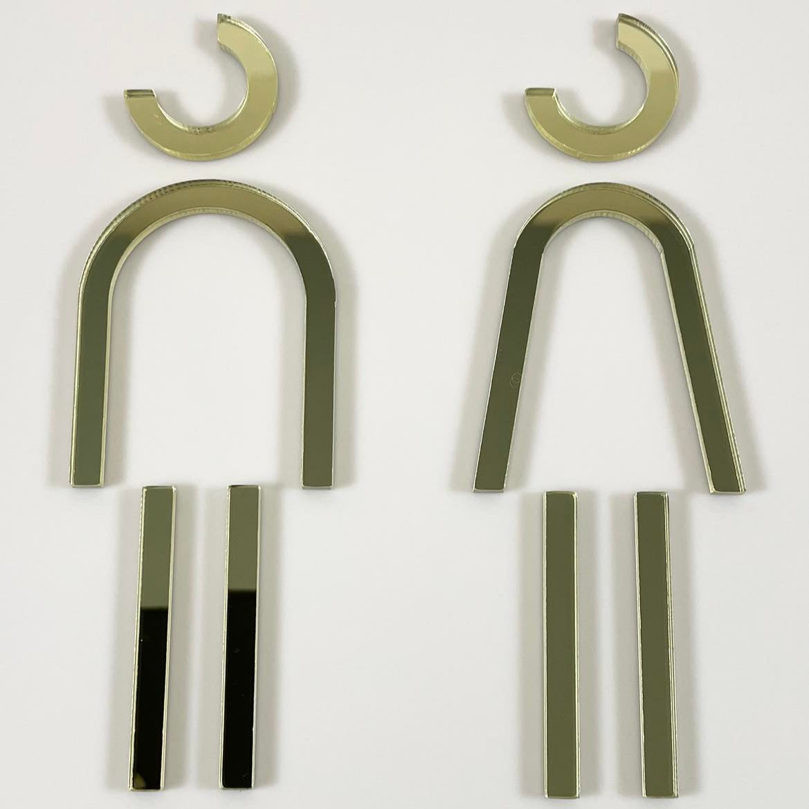 Close‑up of gold acrylic male and female restroom door signs, contemporary bathroom signage