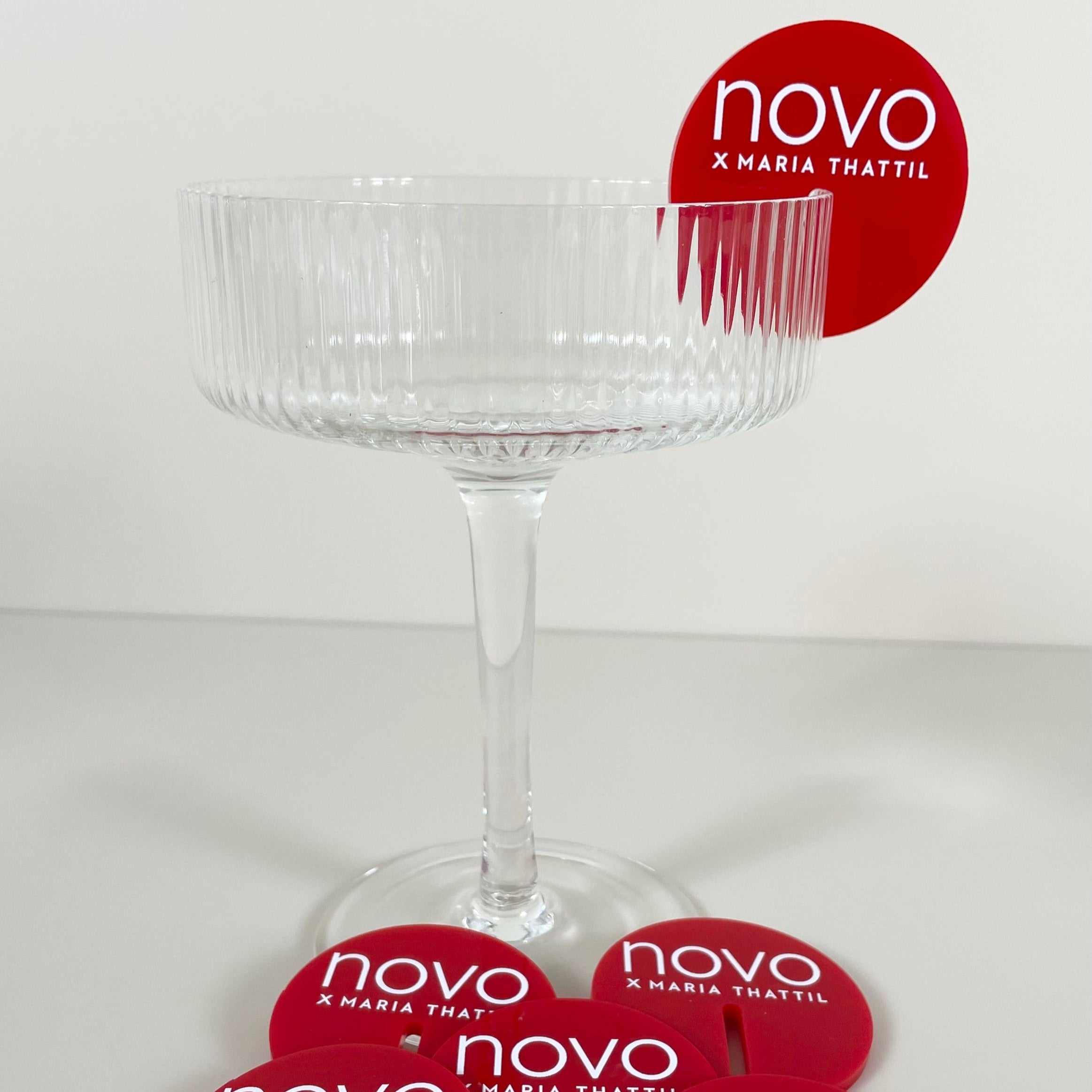 Red branded drink tag with logo on an elegant coupe glass