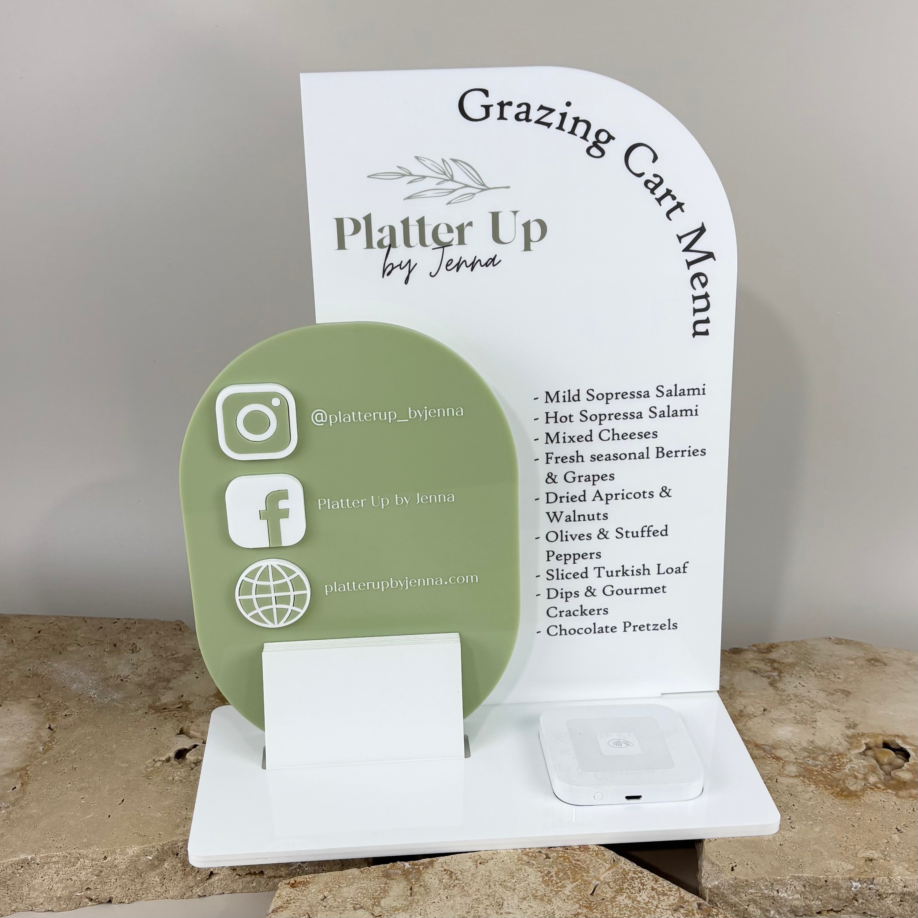 Custom acrylic grazing cart menu and social media display for Platter Up by Jenna, featuring sage green and white layered signage with Instagram, Facebook and website icons, card holder and Square reader tray, styled on a stone surface.