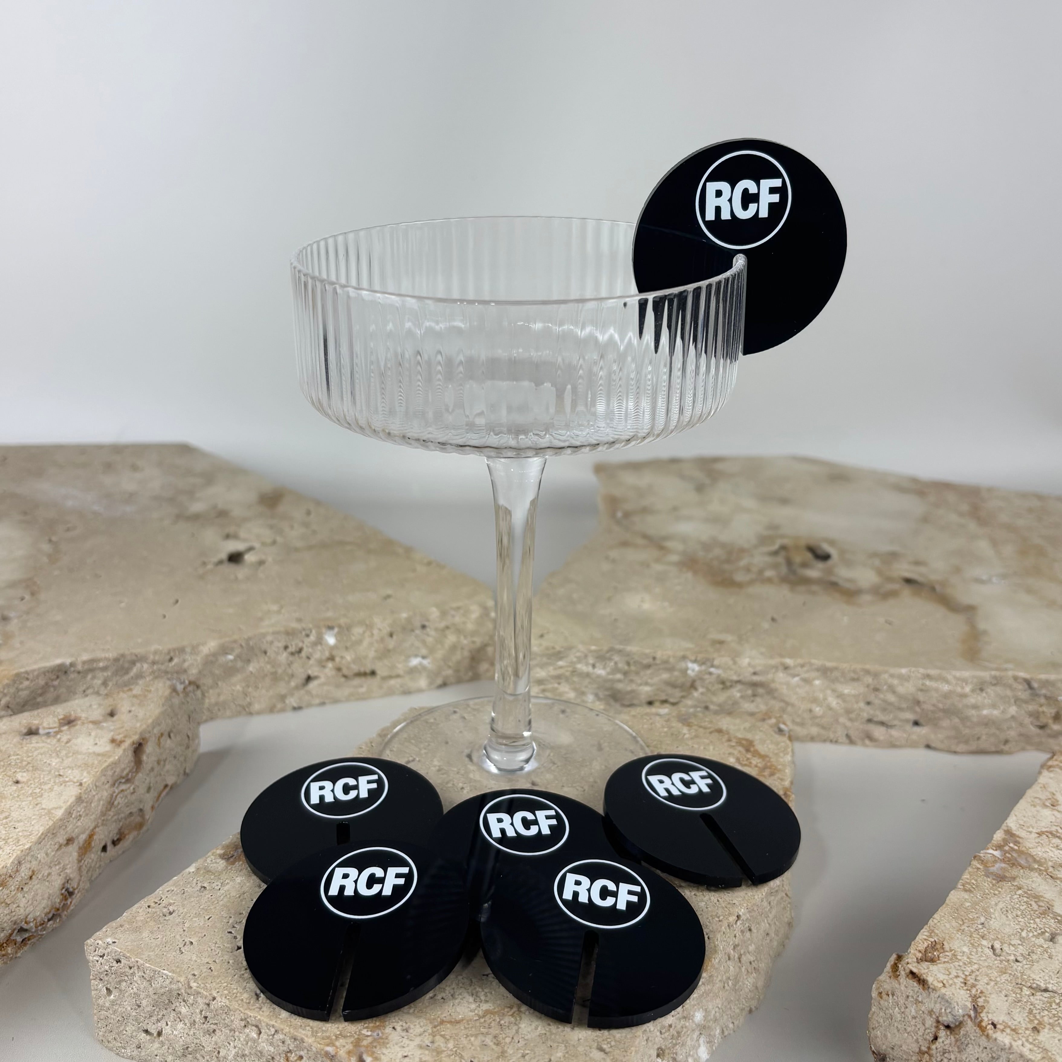 Custom acrylic drink markers with logo branding displayed on a champagne coupe glass, ideal for weddings, events, and corporate functions.
