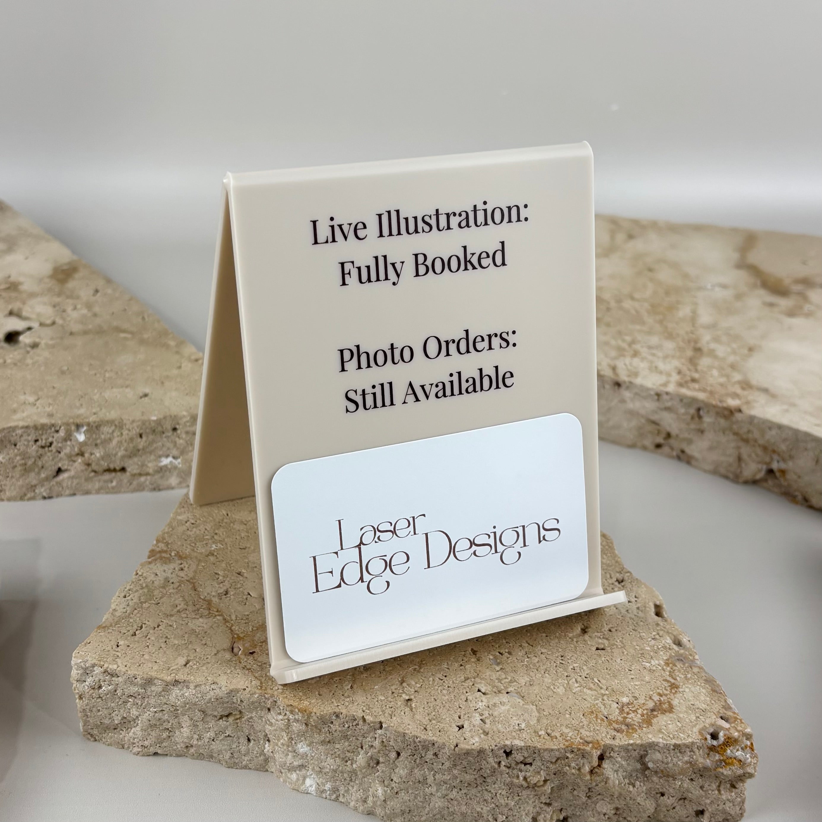 White acrylic countertop sign with UV printed text and integrated business card holder, designed for artists, photographers and market stalls to display booking availability while showcasing business cards in a clean, professional display.