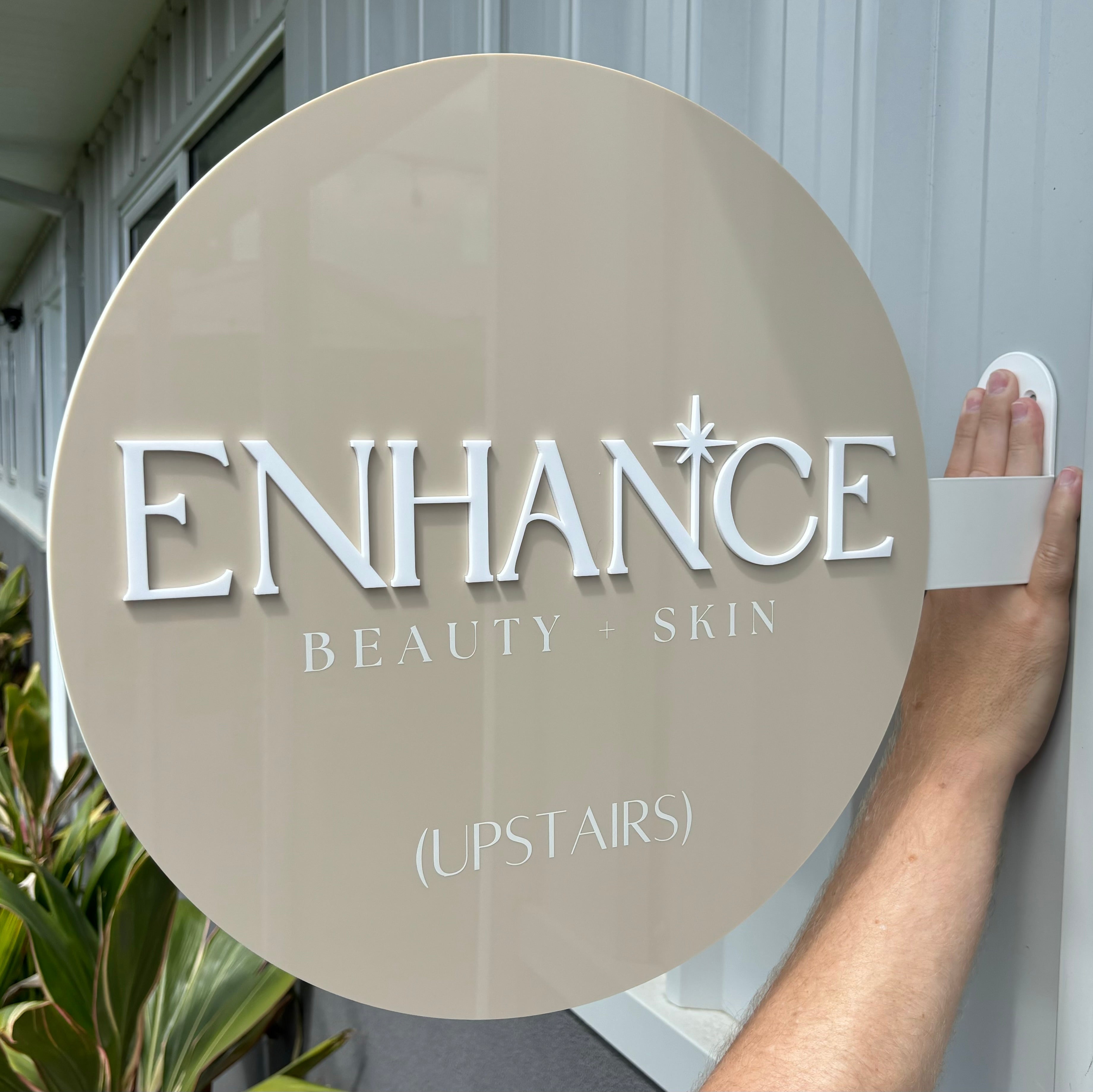 Enhance by Natty Skin neutral-toned round blade sign