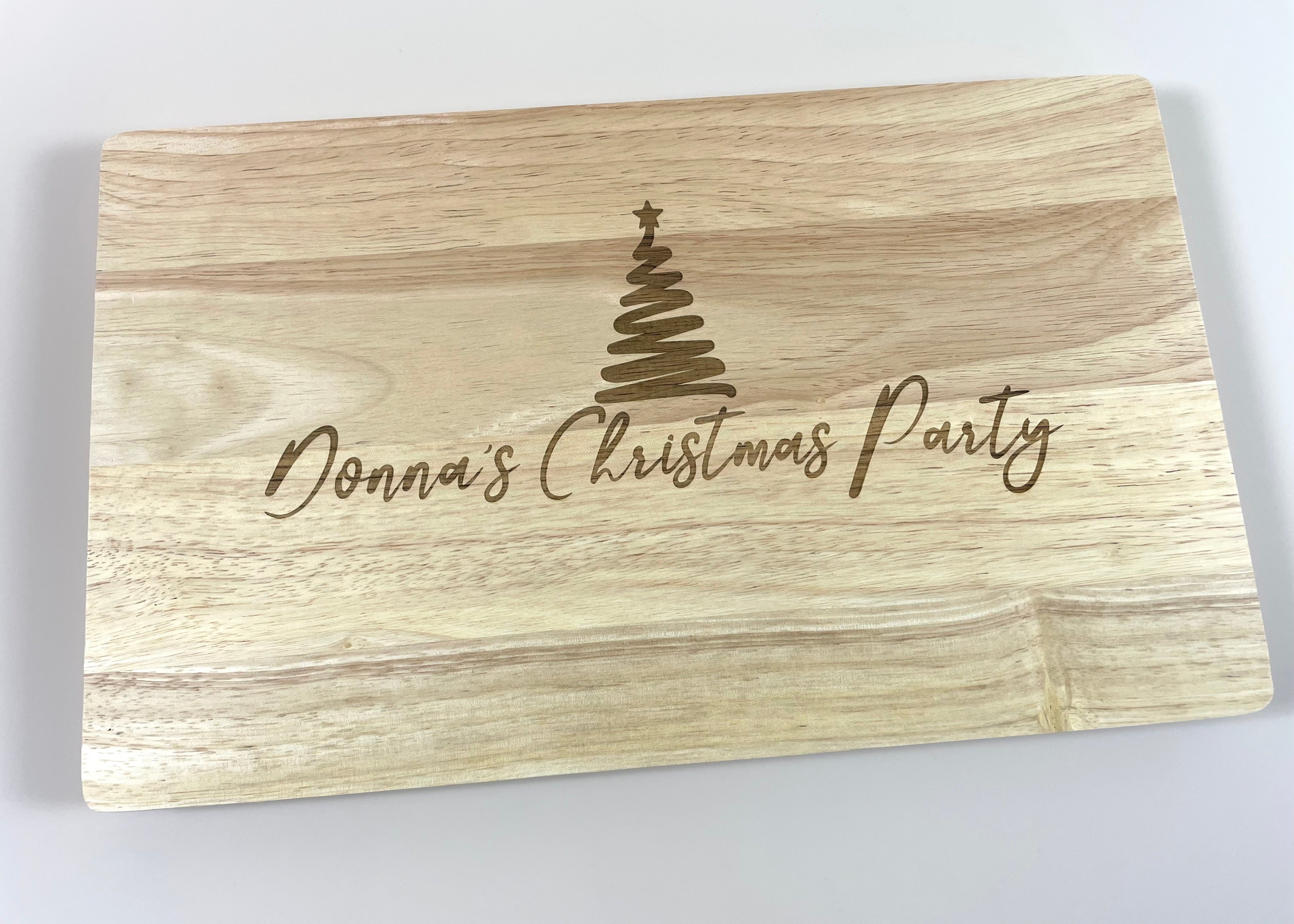 Personalised wooden chopping board for Christmas engraved with custom name and festive tree design