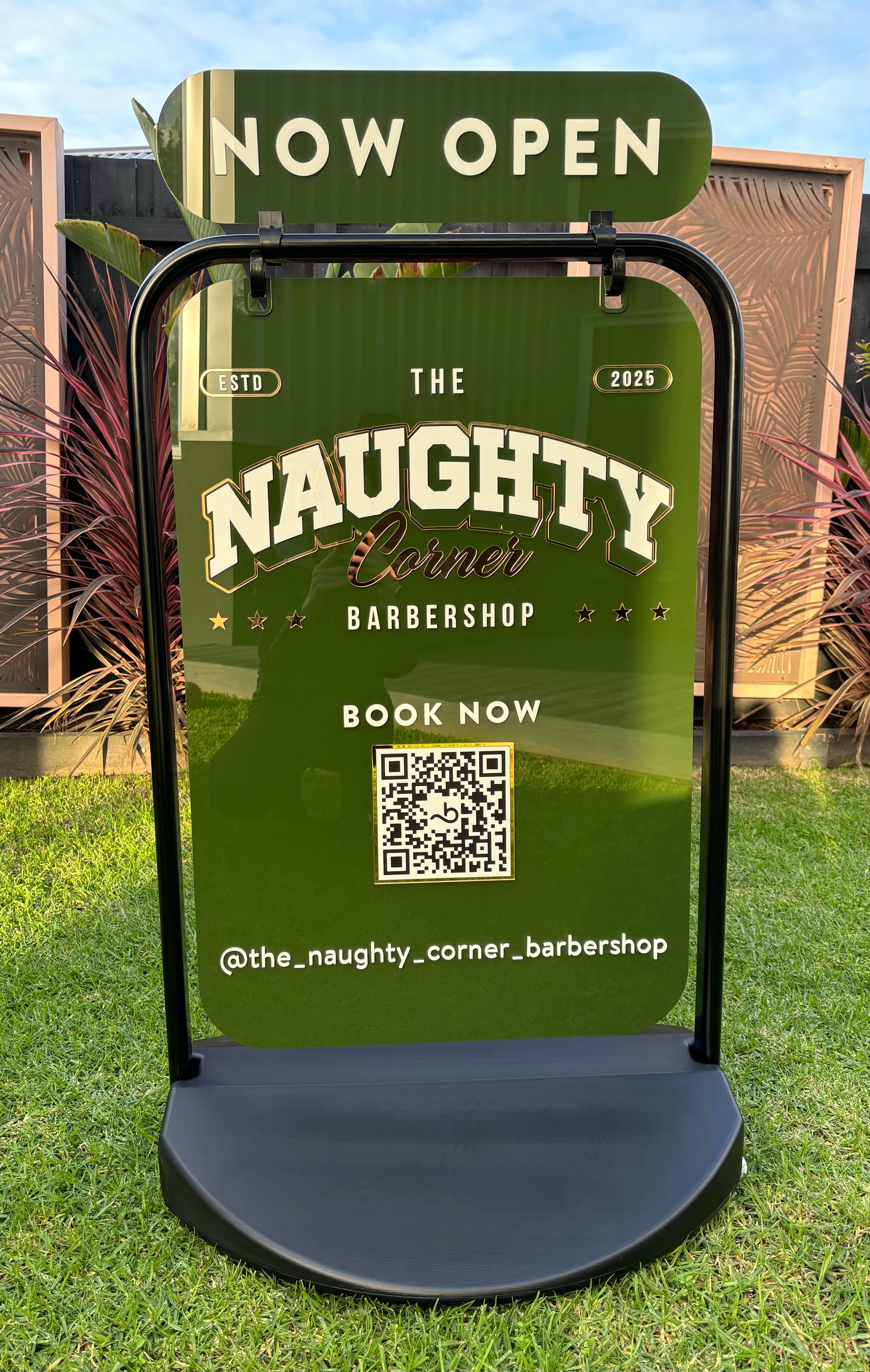Close up of weighted swing sign with The Naughty Corner logo and QR code