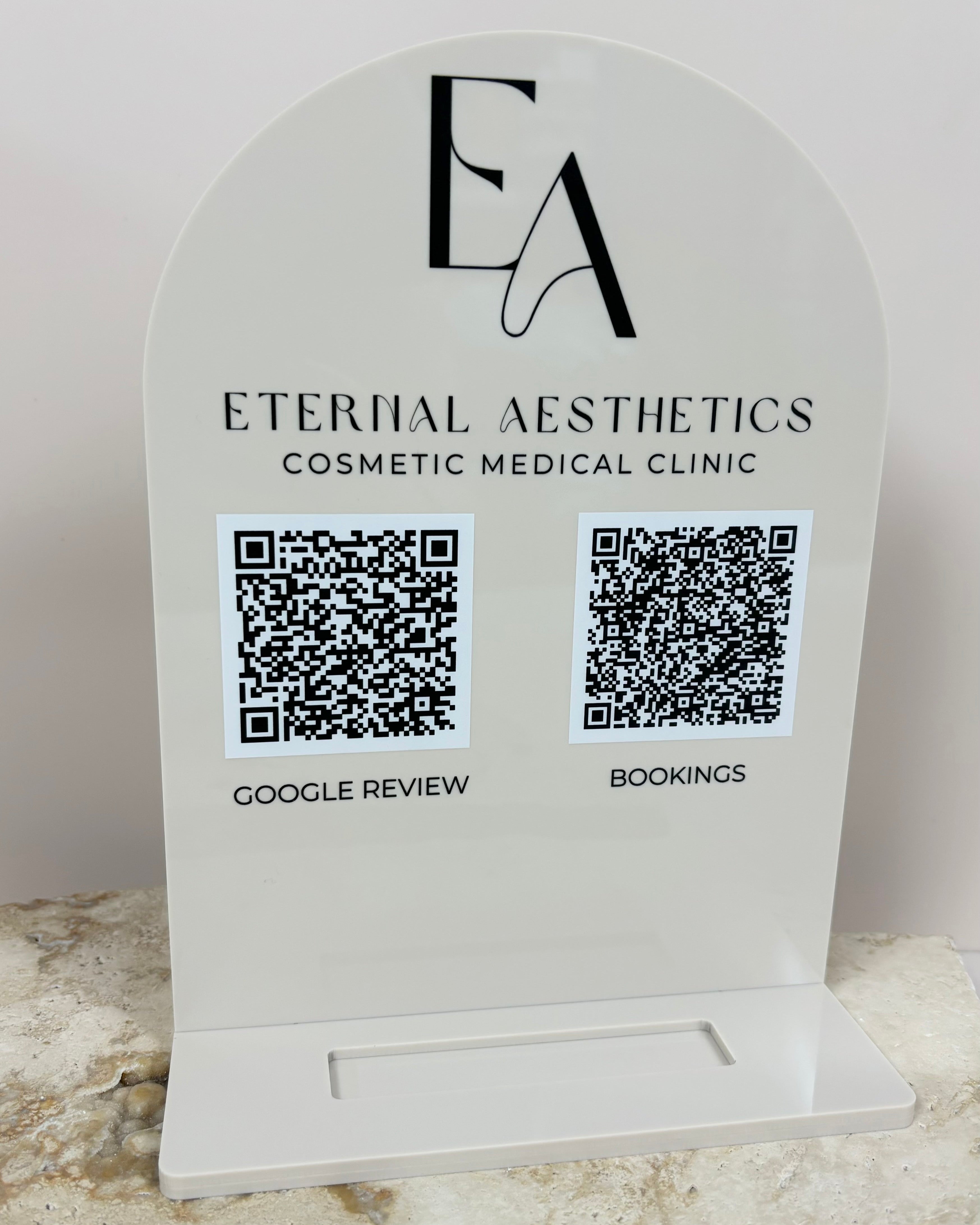 Beige and black card display for Eternal Aesthetics clinic with QR icons