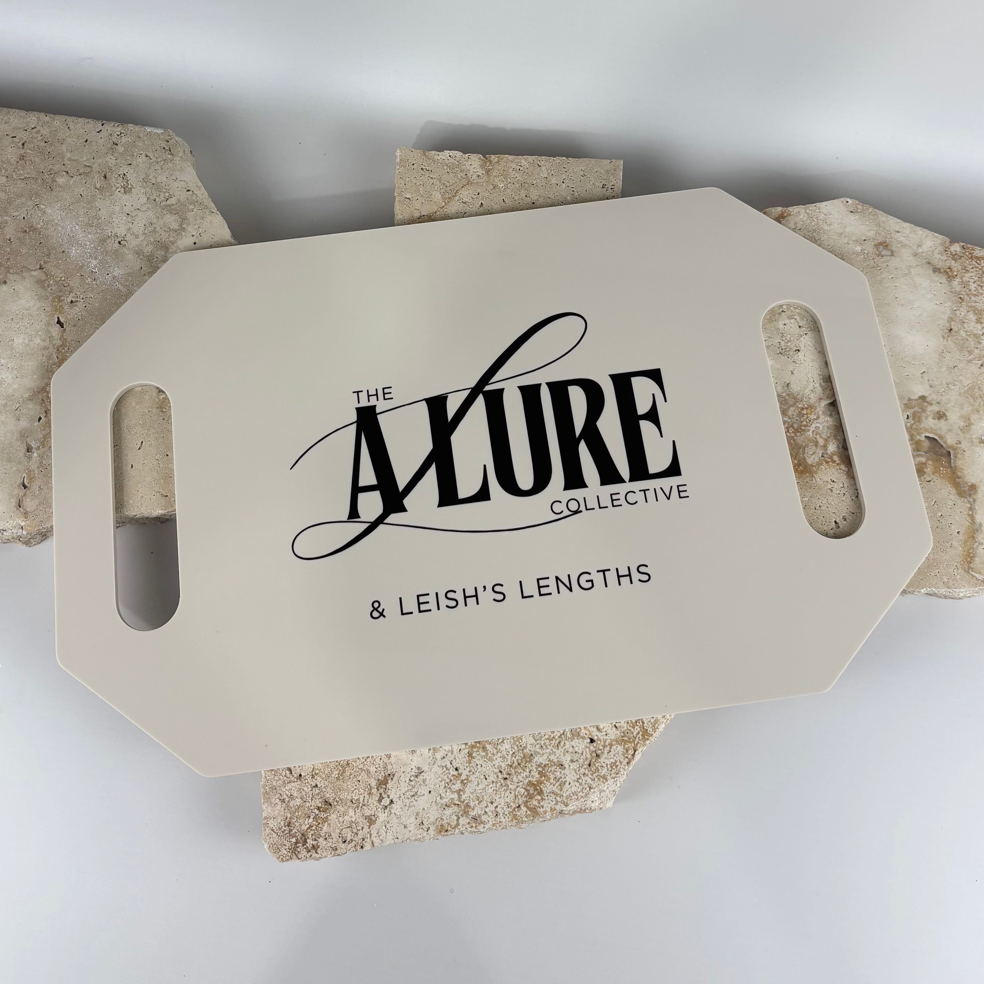 Beige acrylic salon display board featuring “The Allure Collective & Leish’s Lengths” logo in black, styled on textured stone tiles in a clean studio setup.