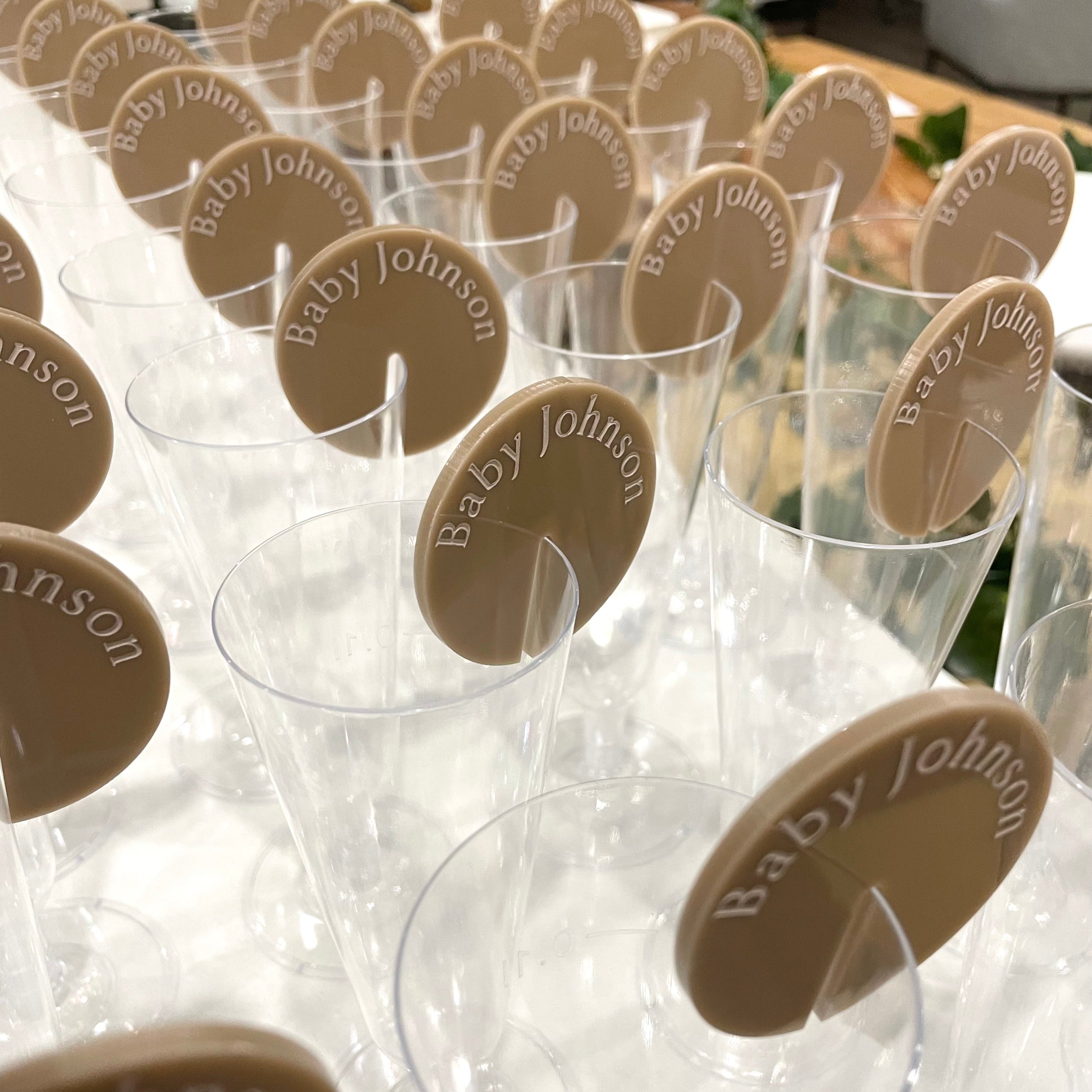 Brown baby shower drink tags clipped to wine glasses at an event