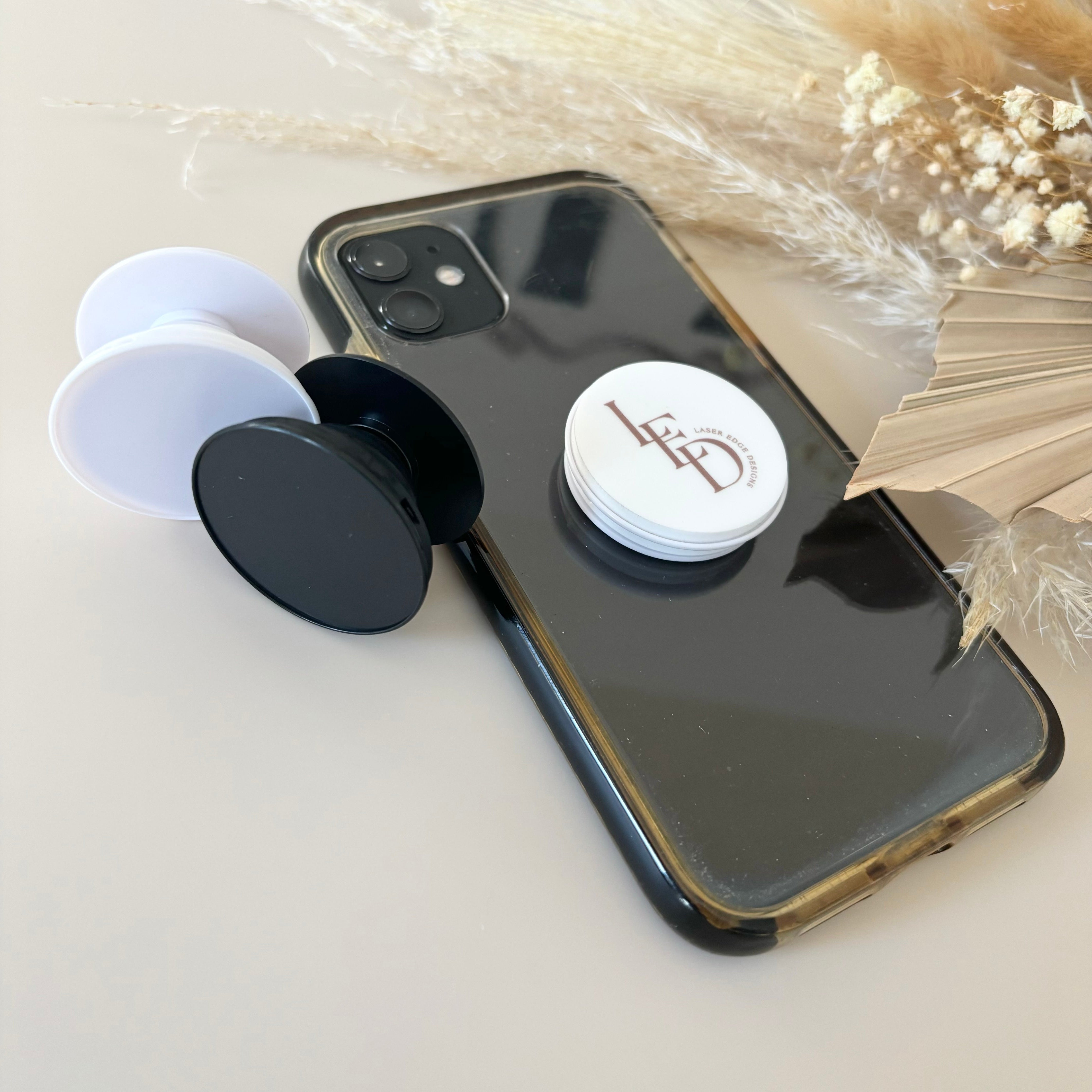 Multiple branded phone grips with logo designs displayed on phone