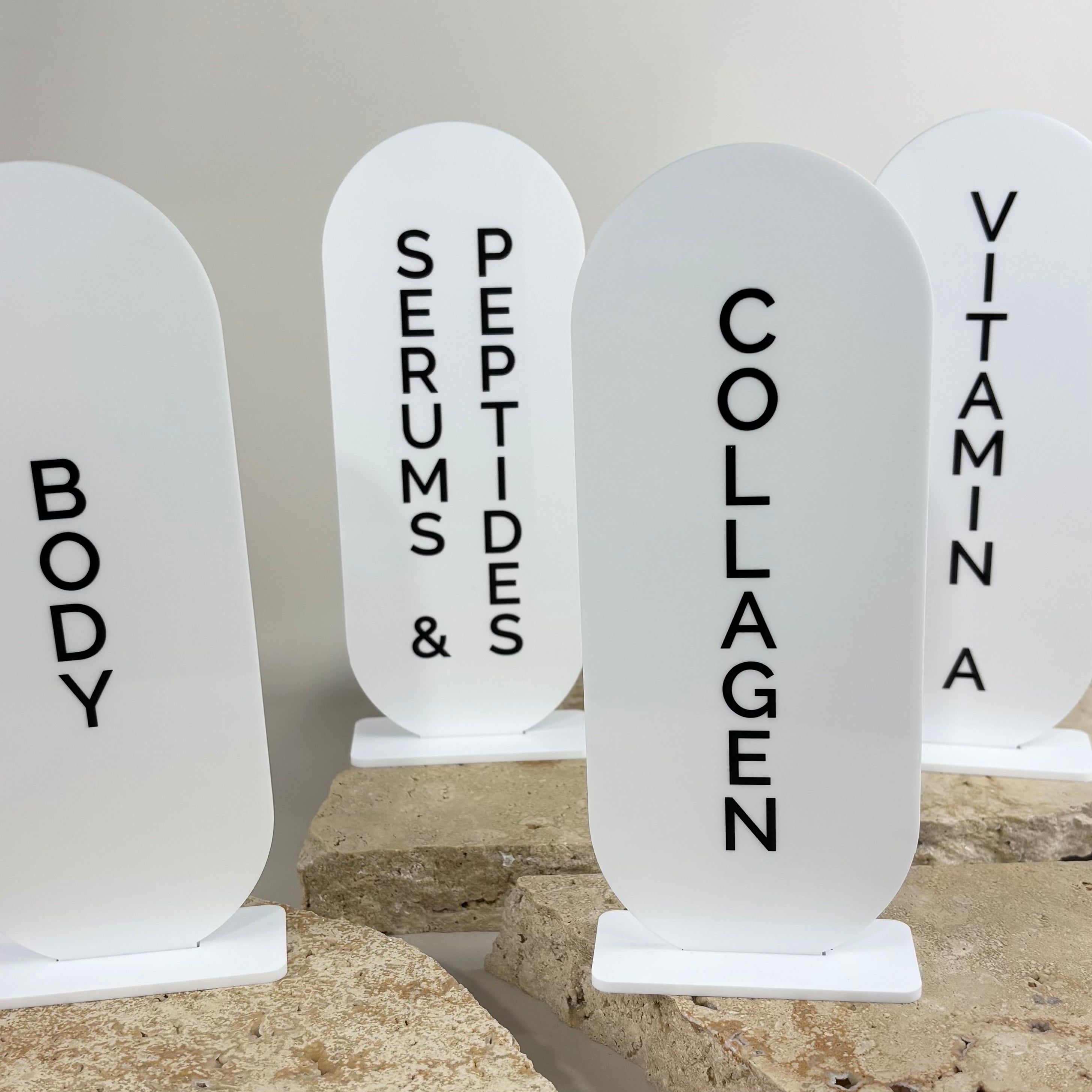 Custom acrylic arch display stands styled on neutral stone risers for beauty clinics, spas and salon retail product organisation