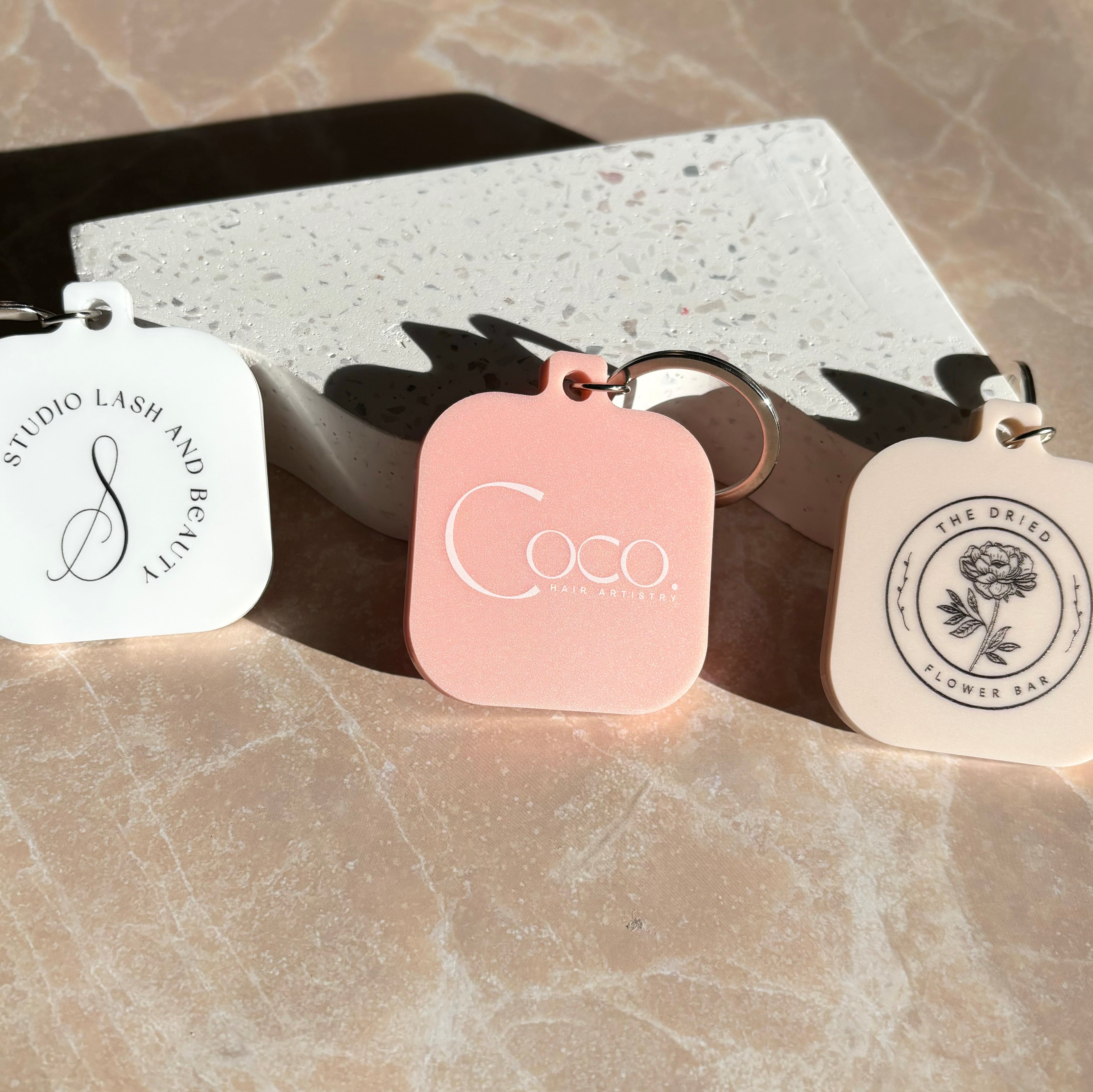 Matte black, white, and peach NFC keychains for stylish branding and contact sharing