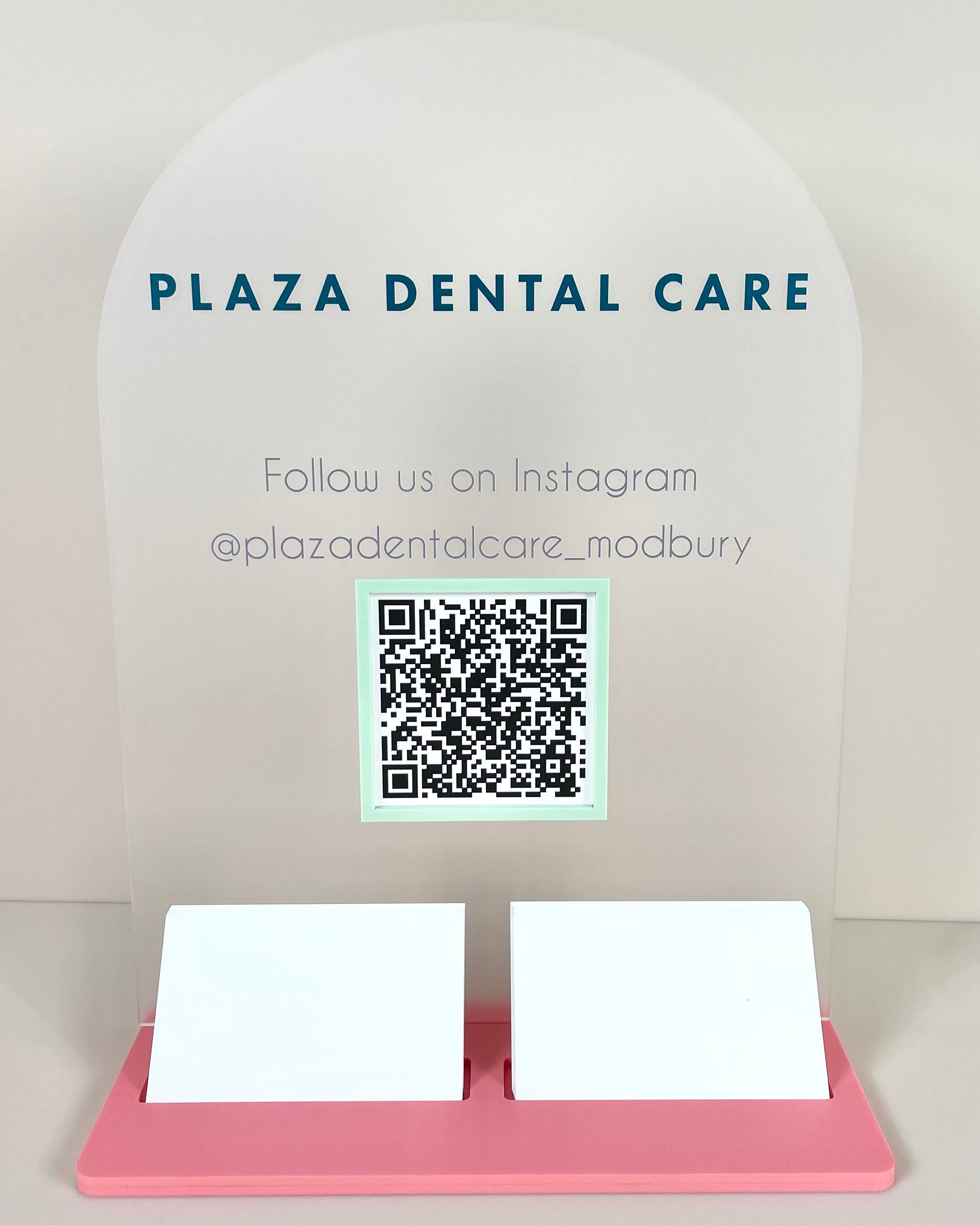 Frosted acrylic business display with Plaza Dental Care logo and QR link