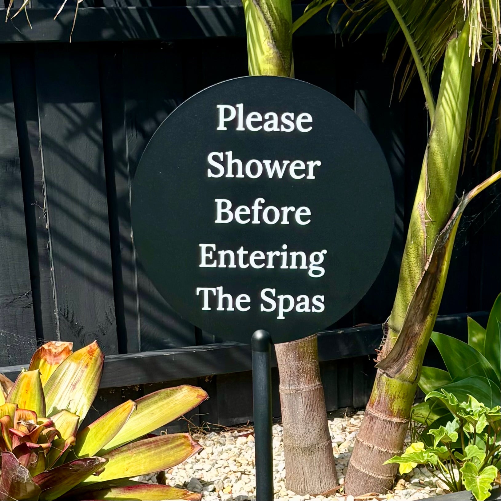 Black round acrylic spa sign “please shower before entering the spas” freestanding business signage for resorts and wellness centres