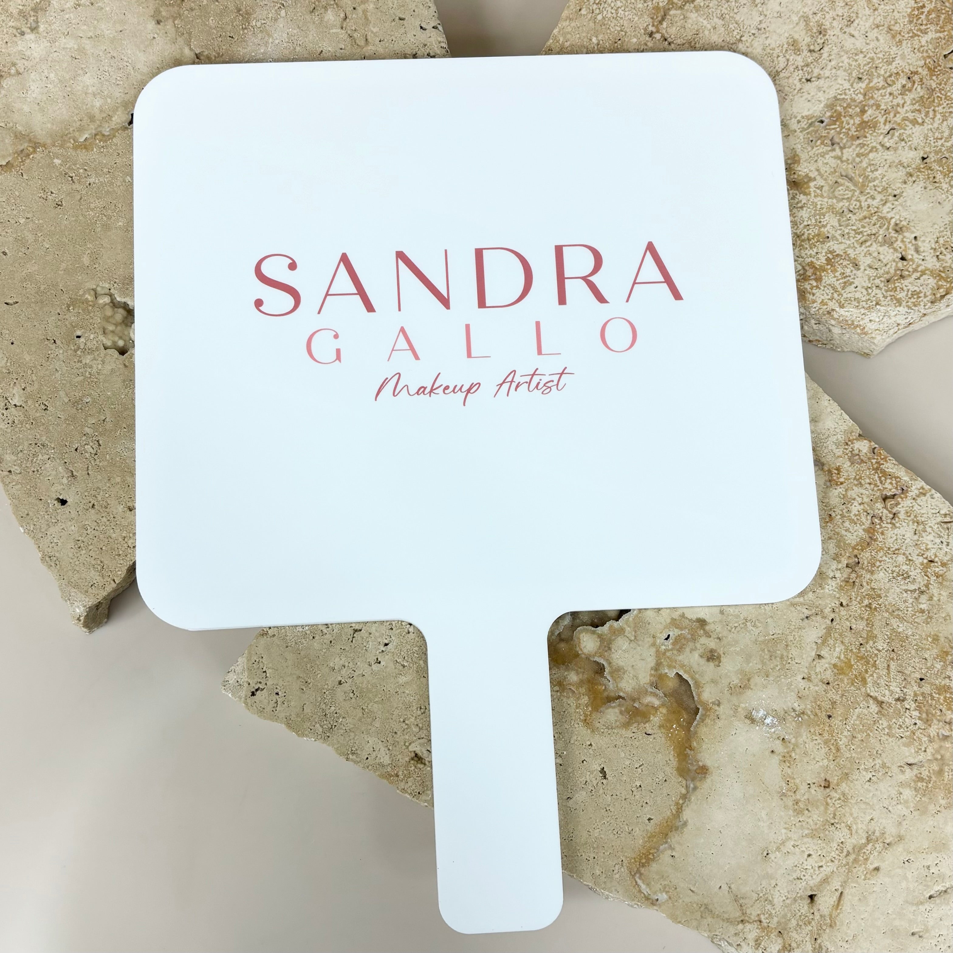 Sandra Calio logo on white handheld salon mirror