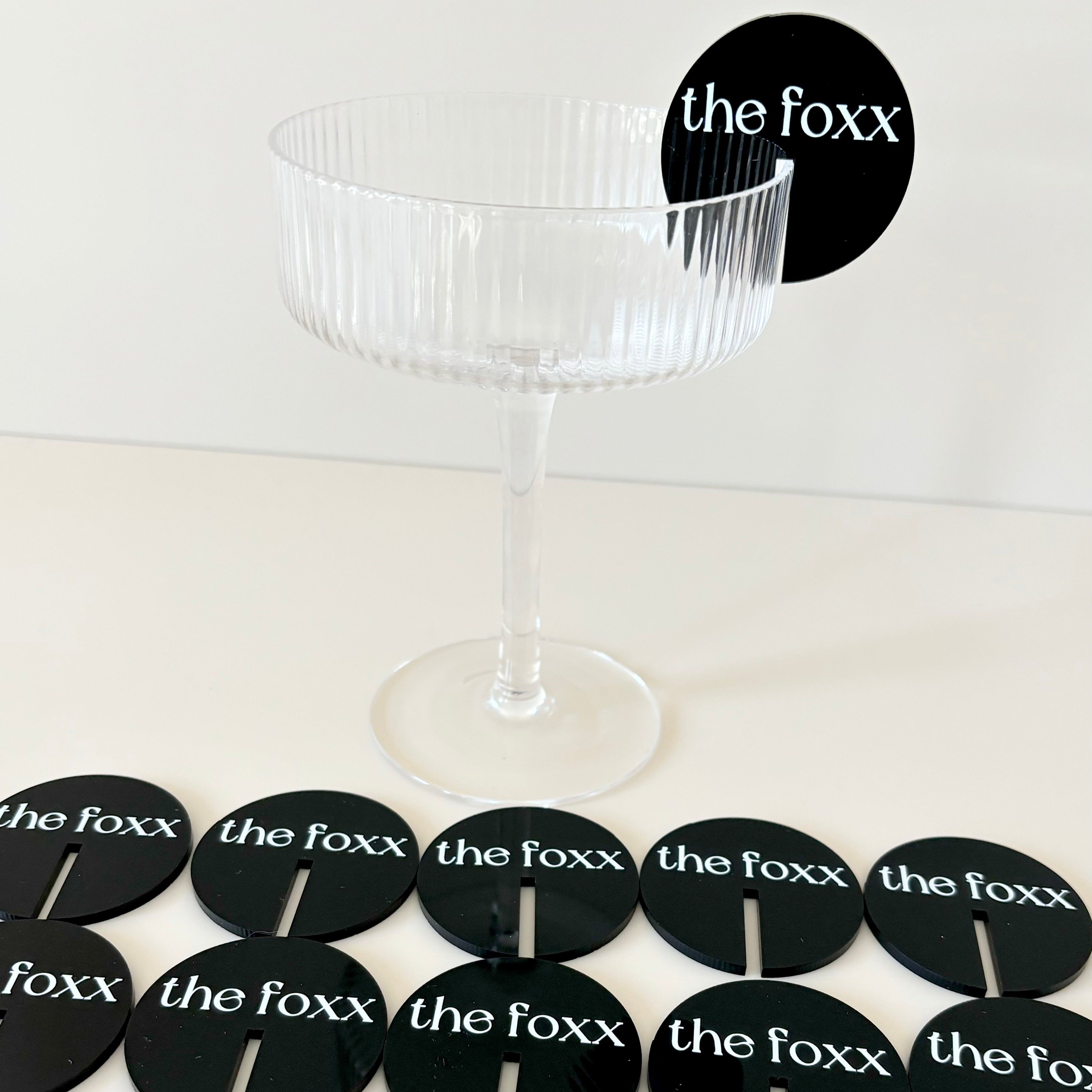 Black logo drink tags with white text on a clear cocktail glass