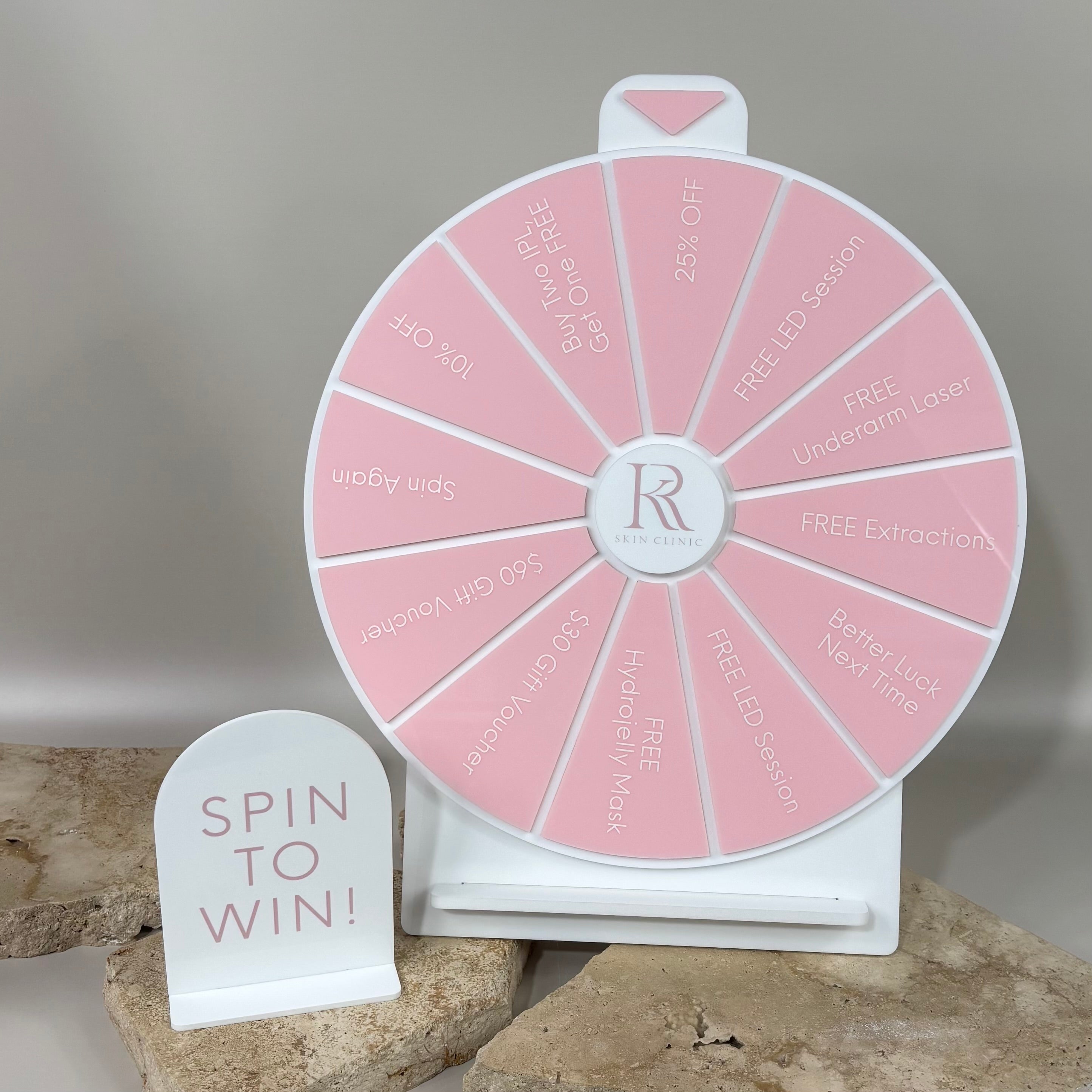 Custom pink spin the wheel prize display for a skin clinic, featuring offers like free LED sessions, discounts, and gift vouchers.