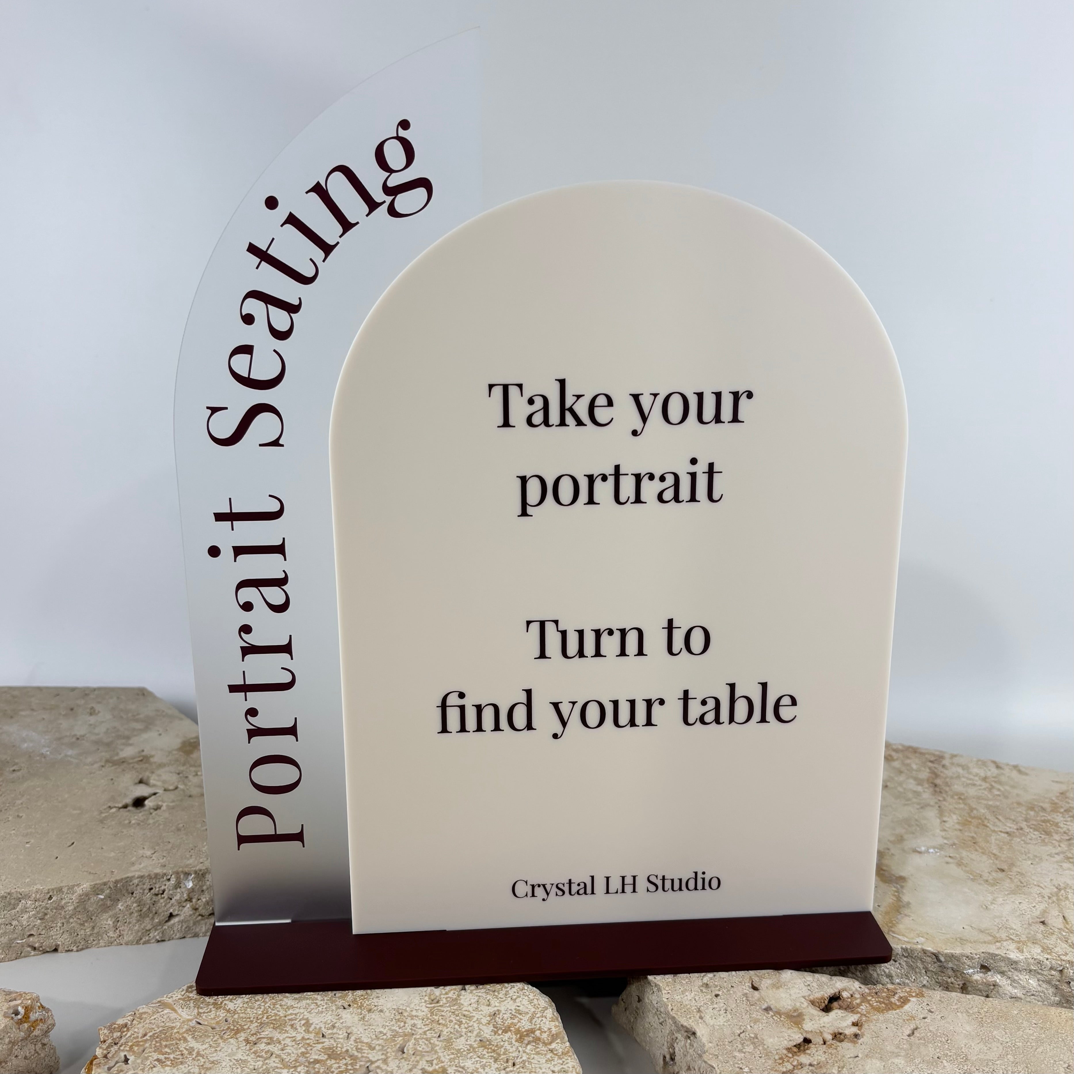 Modern acrylic portrait seating sign with custom wedding or event signage, arched table seating display in neutral tones with burgundy acrylic base, elegant portrait orientation seating chart sign for weddings, functions and special events in Australia