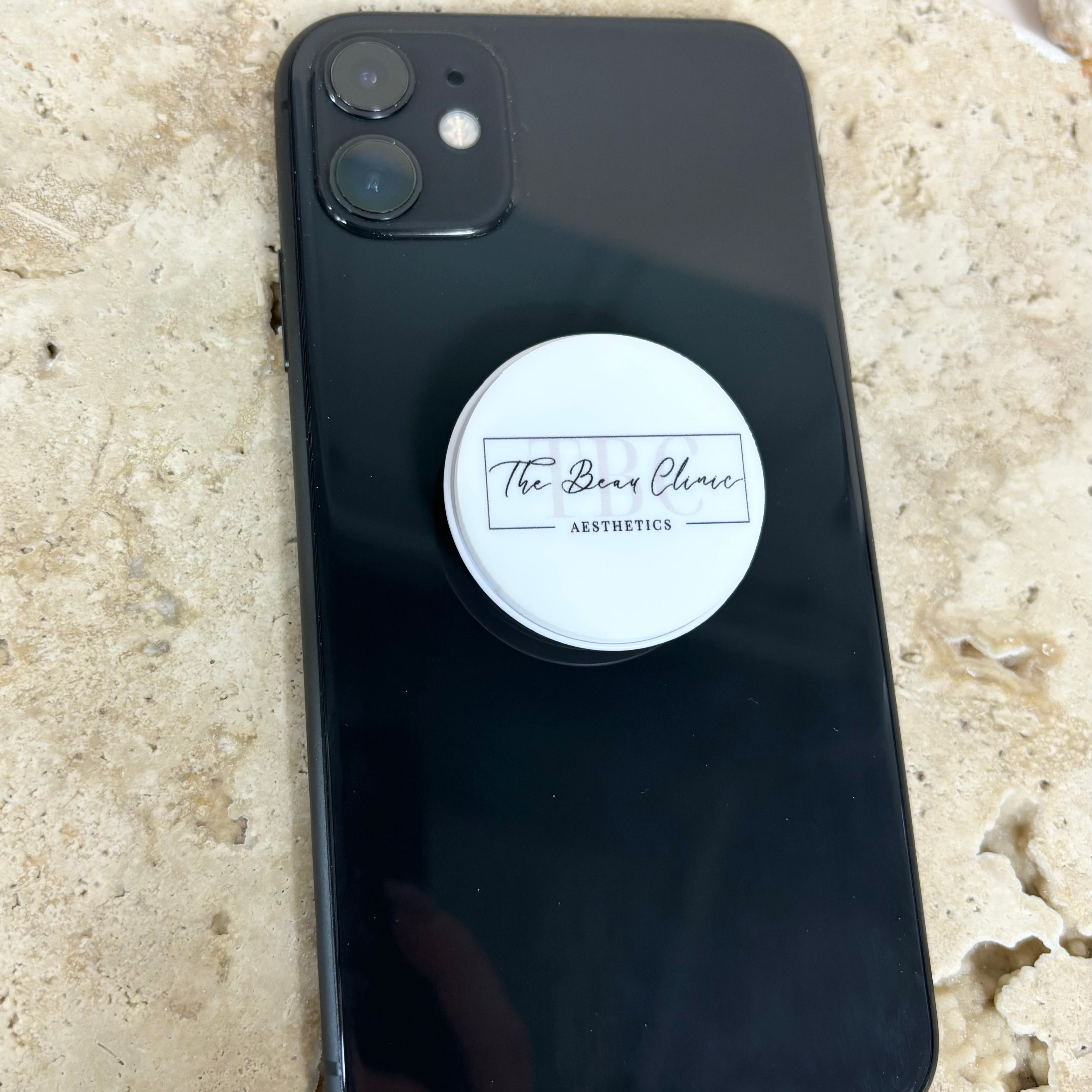 Branded phone grip on black phone case used as a stand
