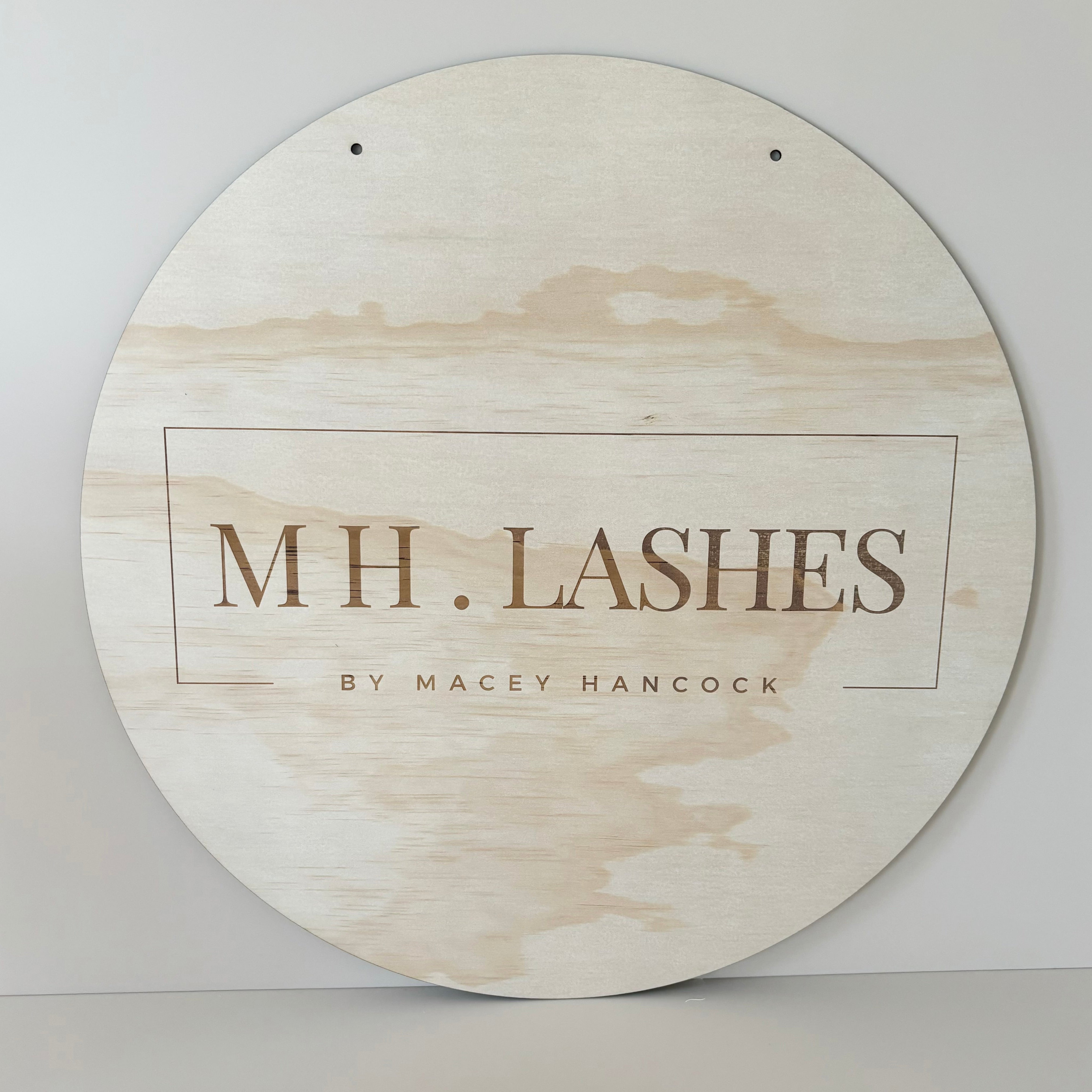 MH Lashes custom engraved timber sign, light wood round sign with fine line business logo and lash brand name.