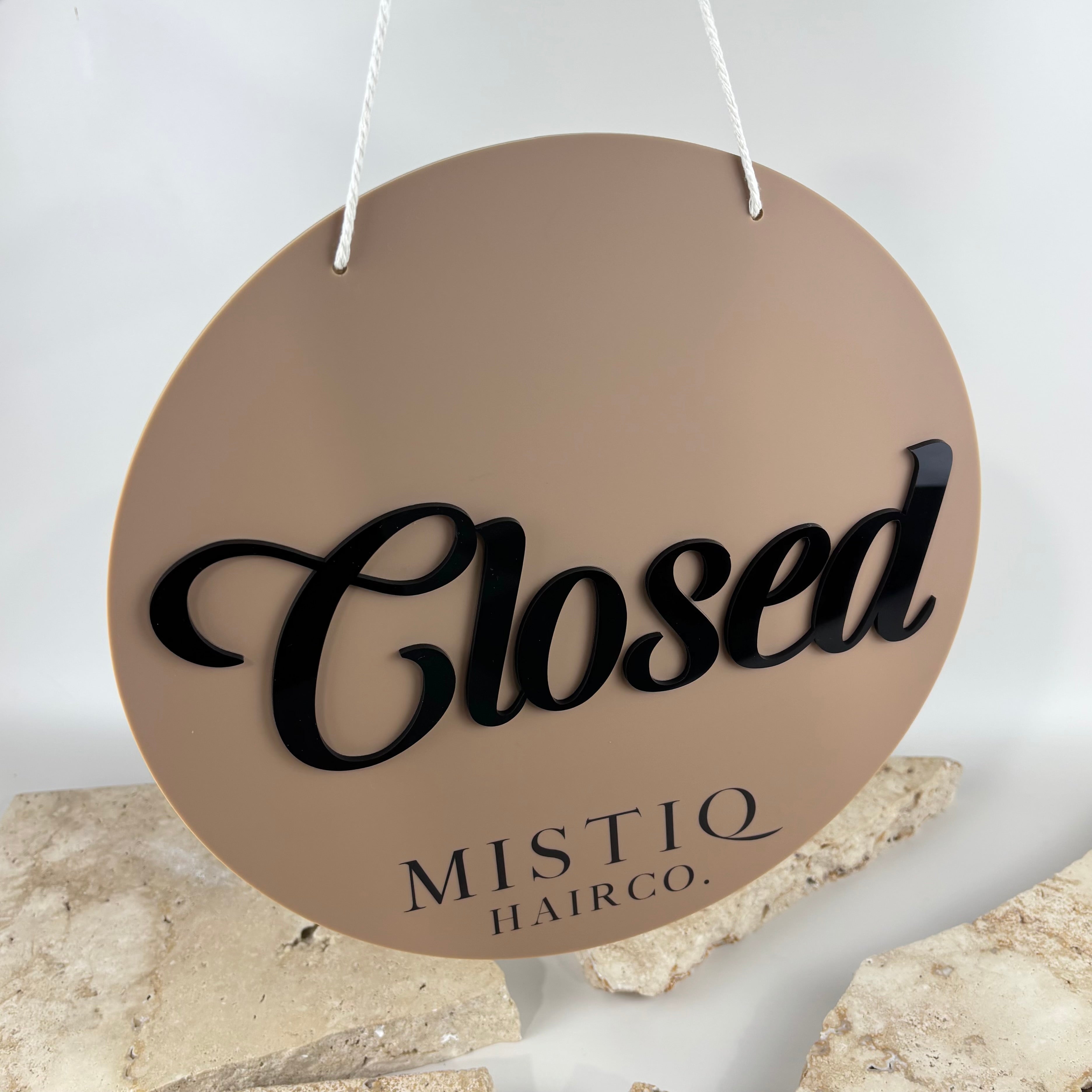 Custom round hanging closed sign for hair salon with 3D black acrylic lettering on a nude beige acrylic background, personalised business door sign for beauty salons, barbers and retail stores.