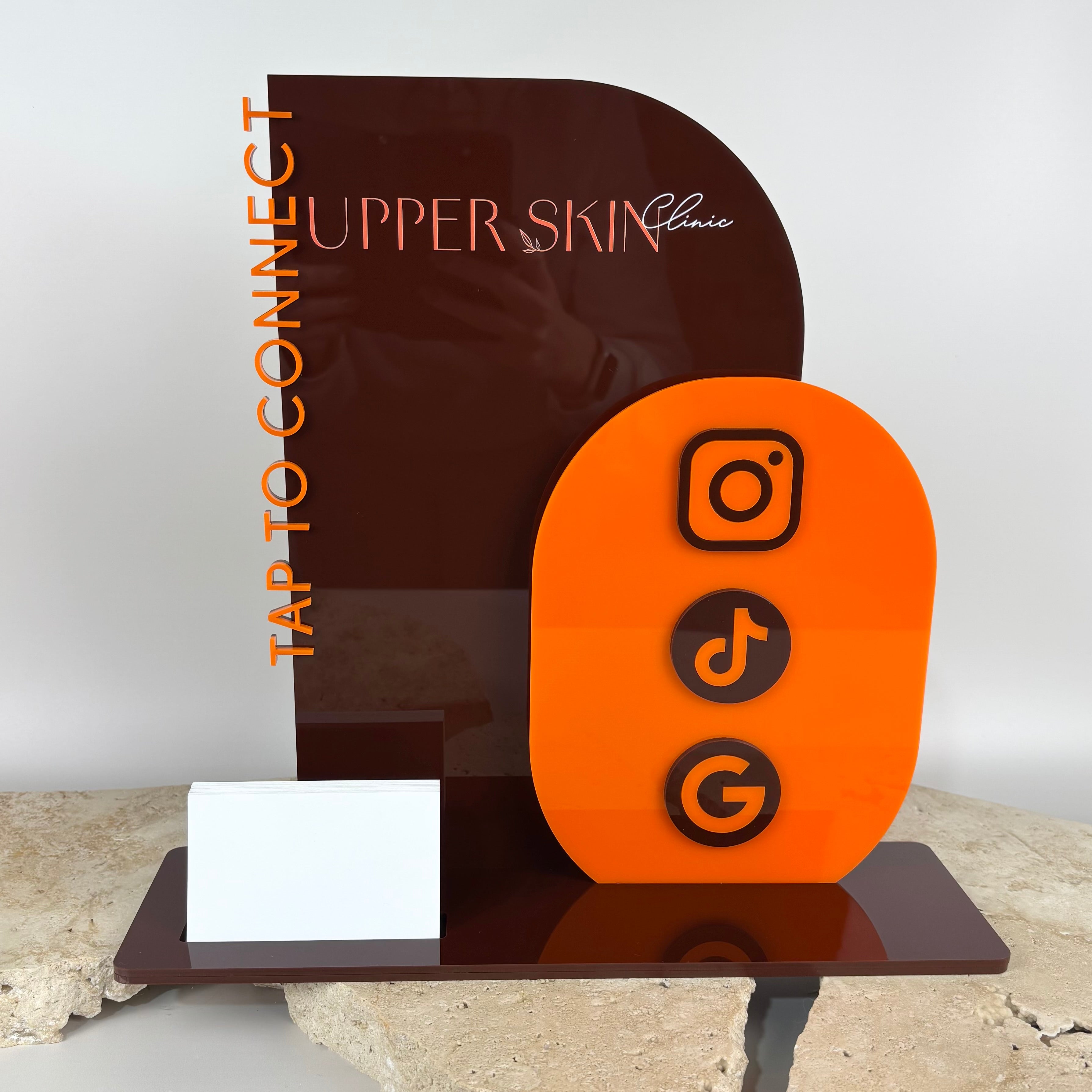 Custom acrylic NFC social media stand in brown and orange with Instagram, TikTok and Google icons for Upper Skin Clinic, featuring ‘Tap to Connect’ text and business card holder, designed for salons and businesses Australia wide