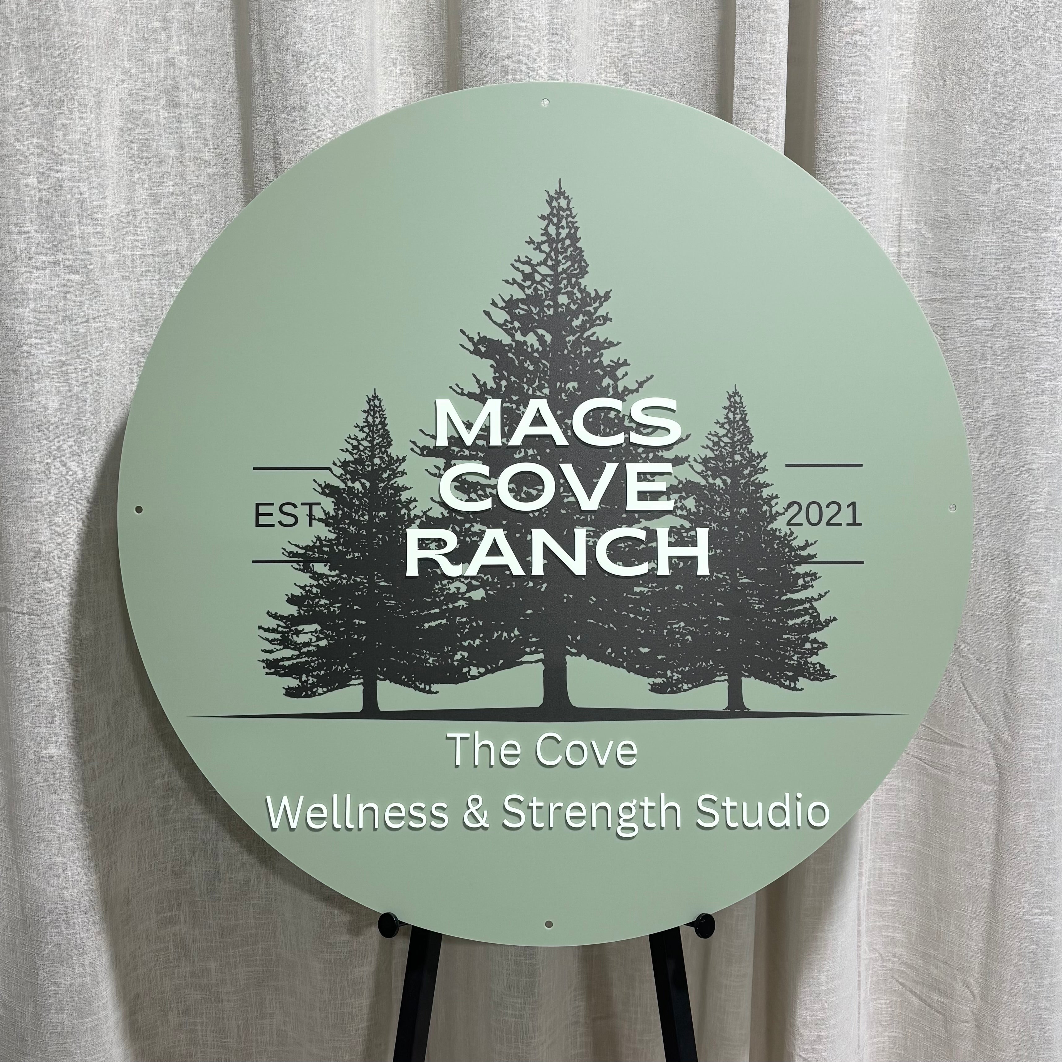 Custom round acrylic business sign featuring UV printed pine tree artwork with raised 3D acrylic lettering. Premium outdoor business signage for wellness studios, fitness centres, ranches and retreat venues, combining full-colour UV printing with layered dimensional text for a professional, high-impact branded display.