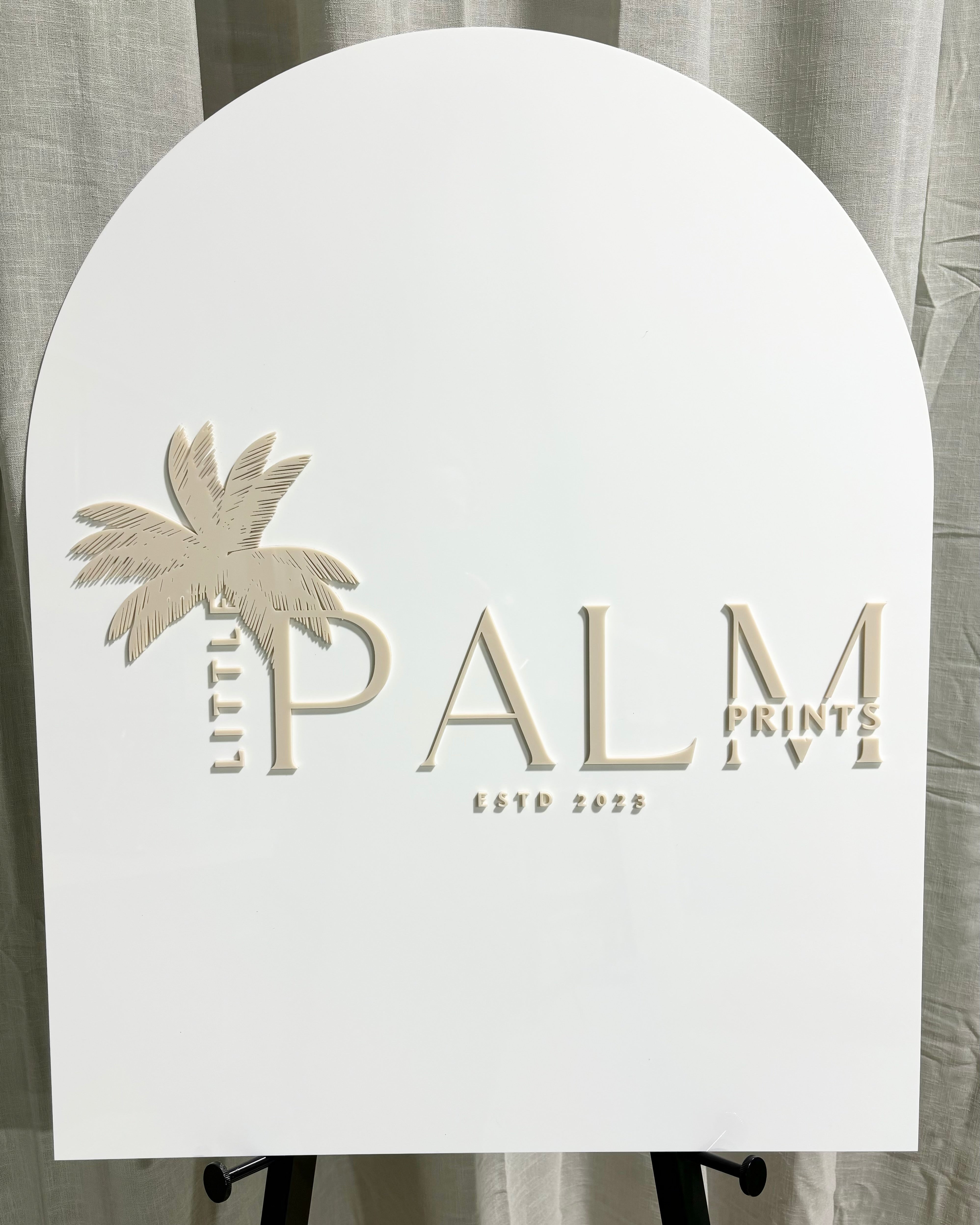 Neutral arch sign with beige palm tree and logo