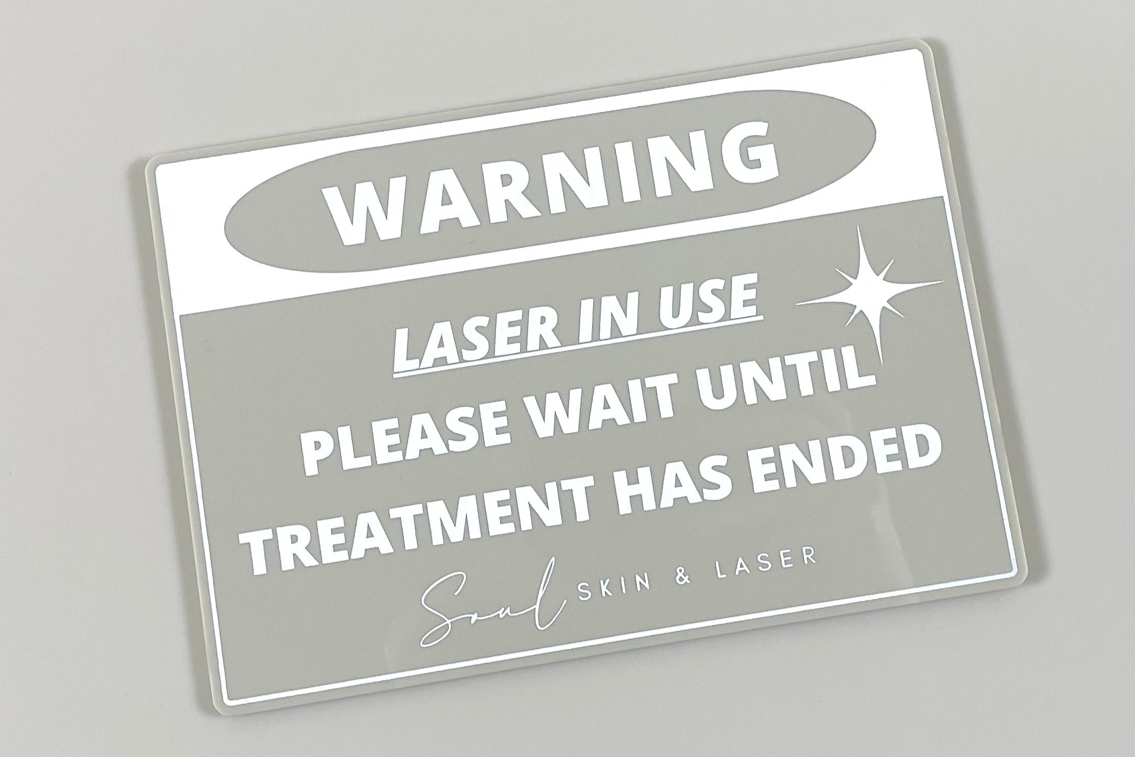 Grey laser treatment in progress warning sign with custom logo for clinic use.
