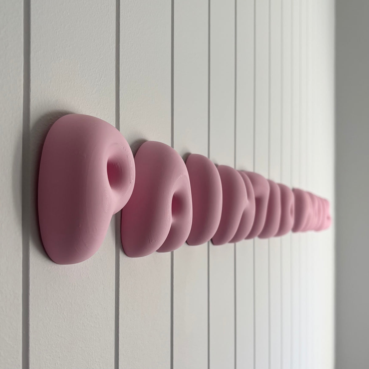 Close-up side view of pink 3D bubble lettering business sign showing the raised dimensional letters mounted on a white wall.