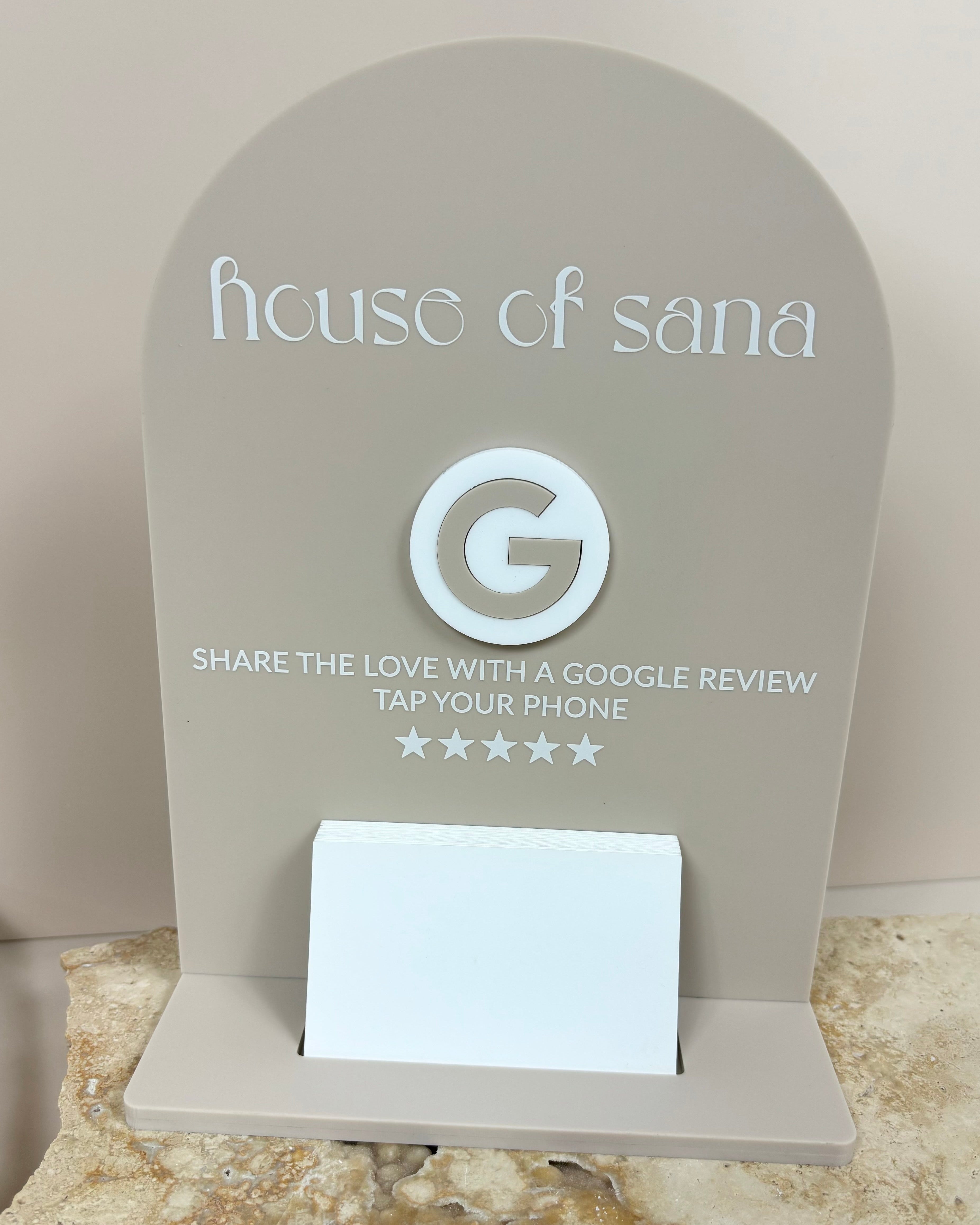 NFC card holder for House of Sana, showing Google review stars and social media icons on a sleek acrylic display.