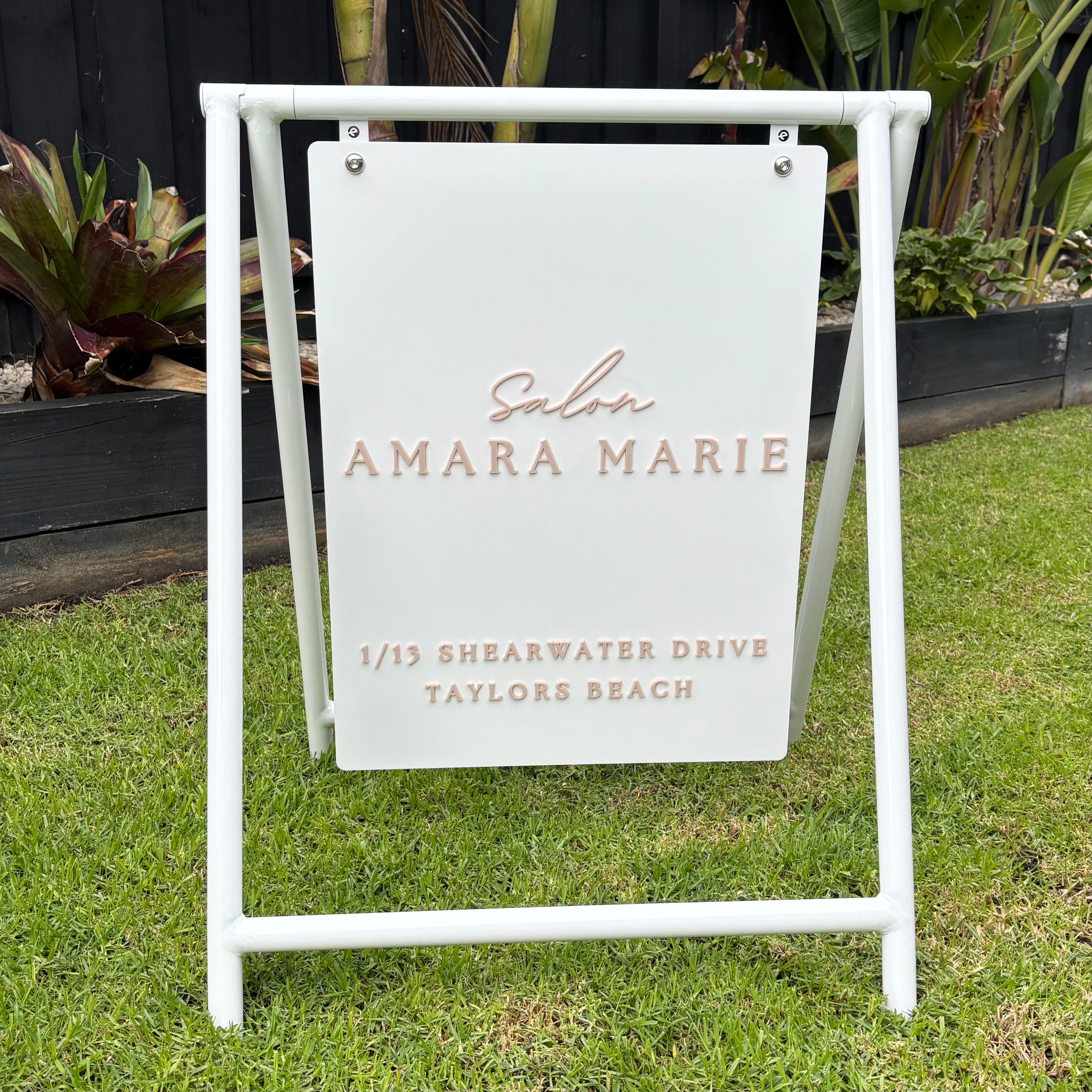Custom white A-frame pavement sign with a powder-coated steel frame and hanging aluminium panel featuring raised 3D acrylic lettering for Salon Amara Marie. Premium outdoor business signage designed for hair salons, beauty salons, cosmetic clinics and retail storefronts, ideal for attracting foot traffic and improving street visibility.