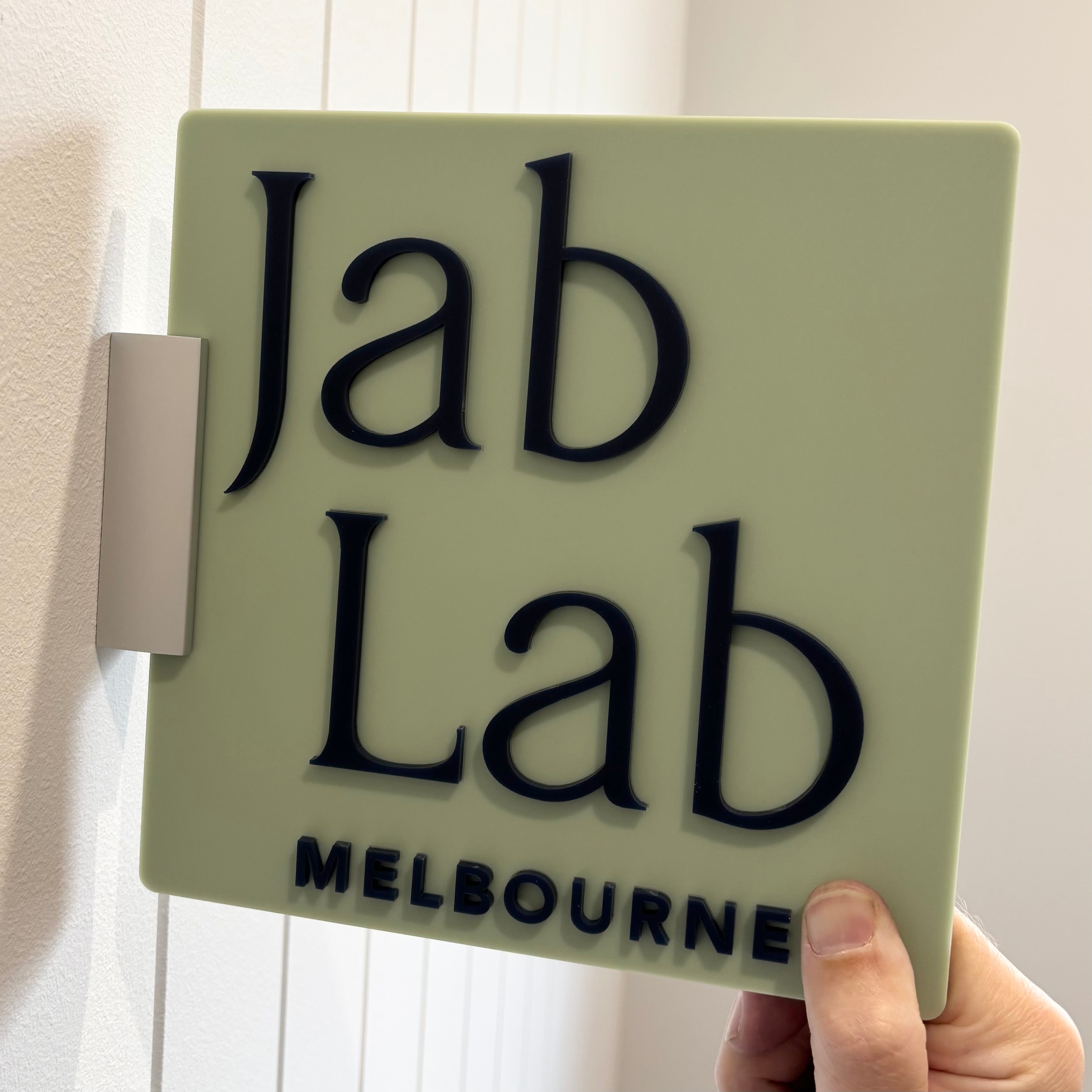 Custom double-sided corridor sign for Jab Lab Melbourne with 3D black acrylic lettering on sage green background, ideal for indoor business signage in clinics or salons
