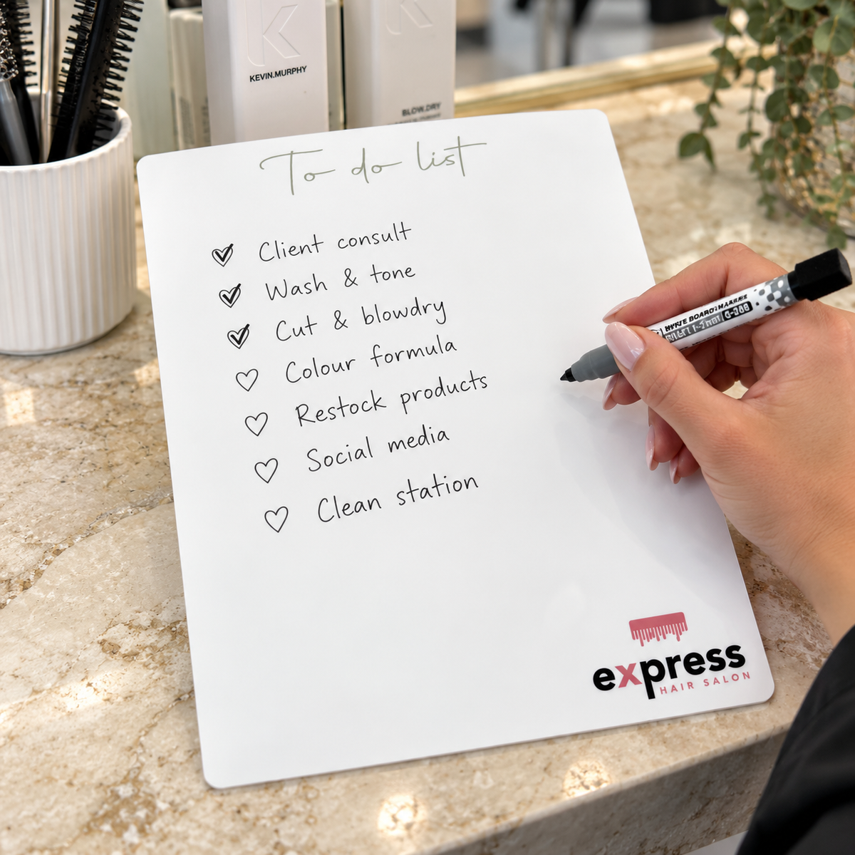 Custom white acrylic dry erase to do list board with Express Hair Salon branding, featuring handwritten tasks and a whiteboard marker on a modern salon counter.