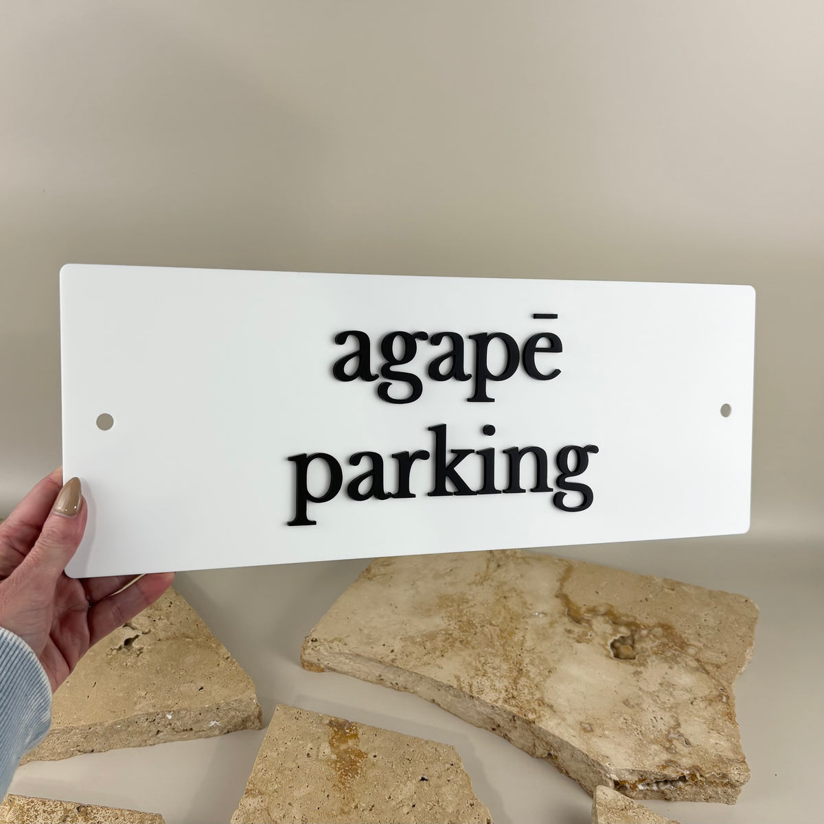 Custom rectangular white acrylic parking sign for Agapē featuring raised black 3D acrylic lettering, rounded corners and two mounting holes for business parking signage.