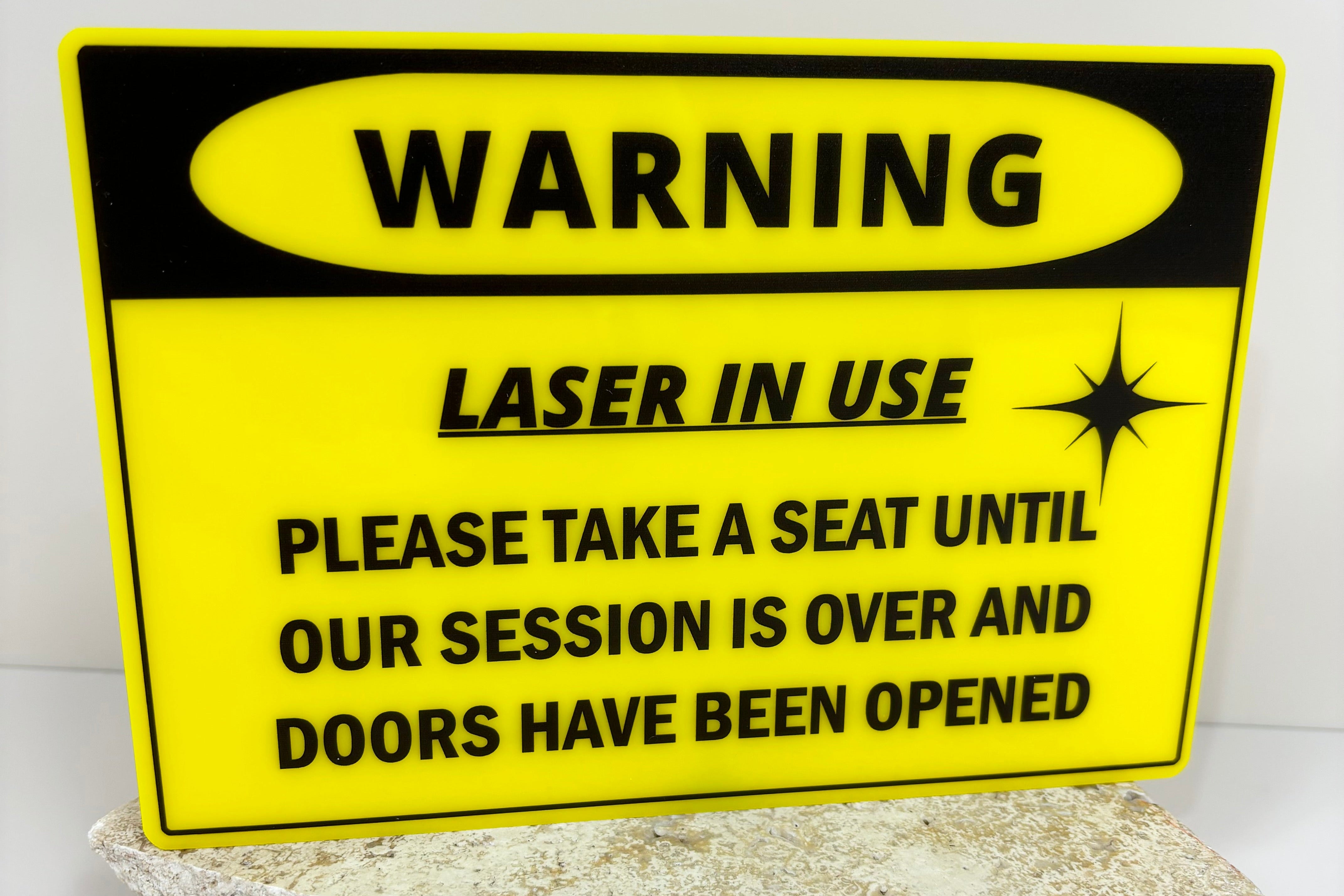 Bright yellow laser treatment warning sign advising clients to wait outside.