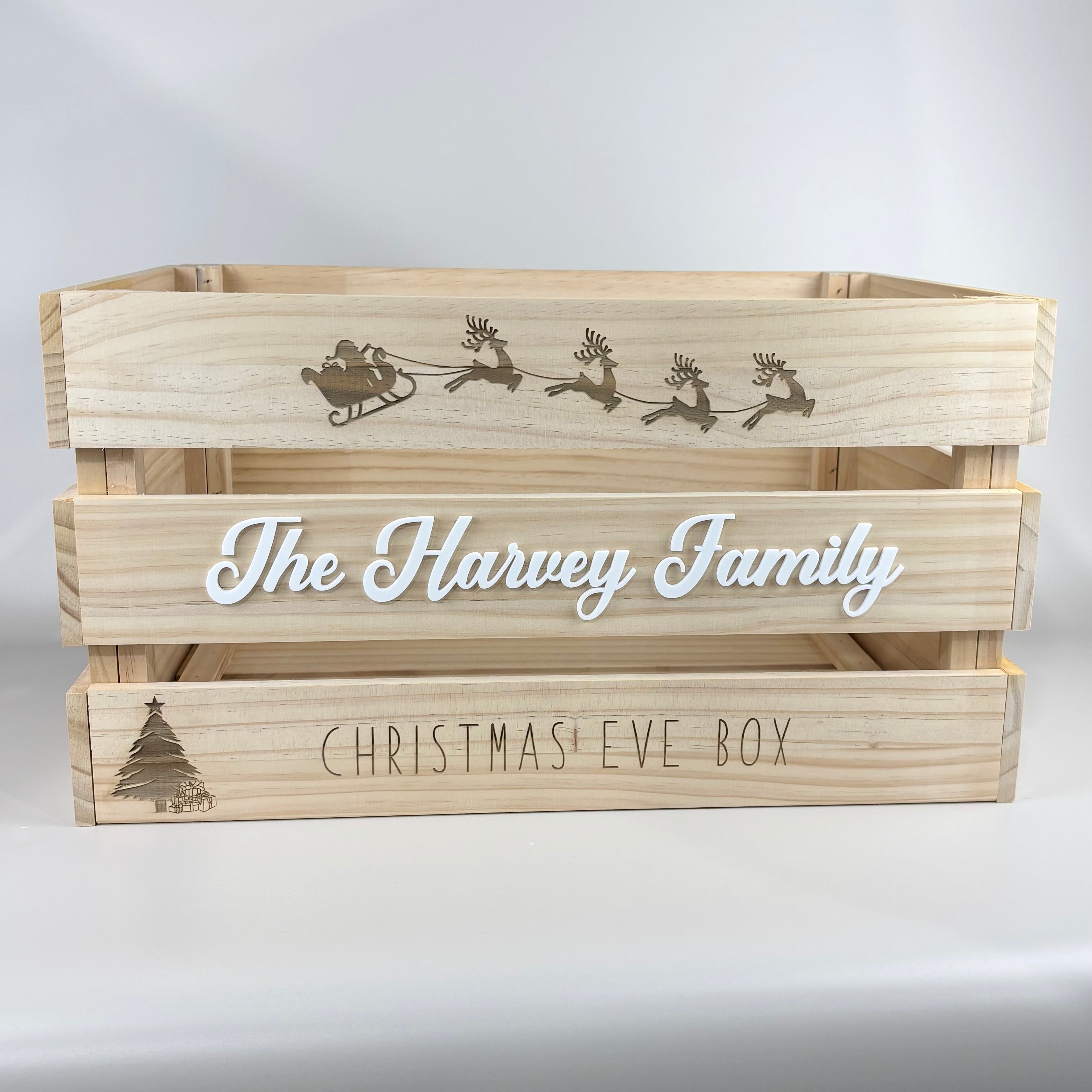 Personalised wooden Christmas Eve box engraved with Santa’s sleigh and reindeer, featuring custom white acrylic name “The Harvey Family” and engraved text “Christmas Eve Box,” perfect for family Christmas traditions.
