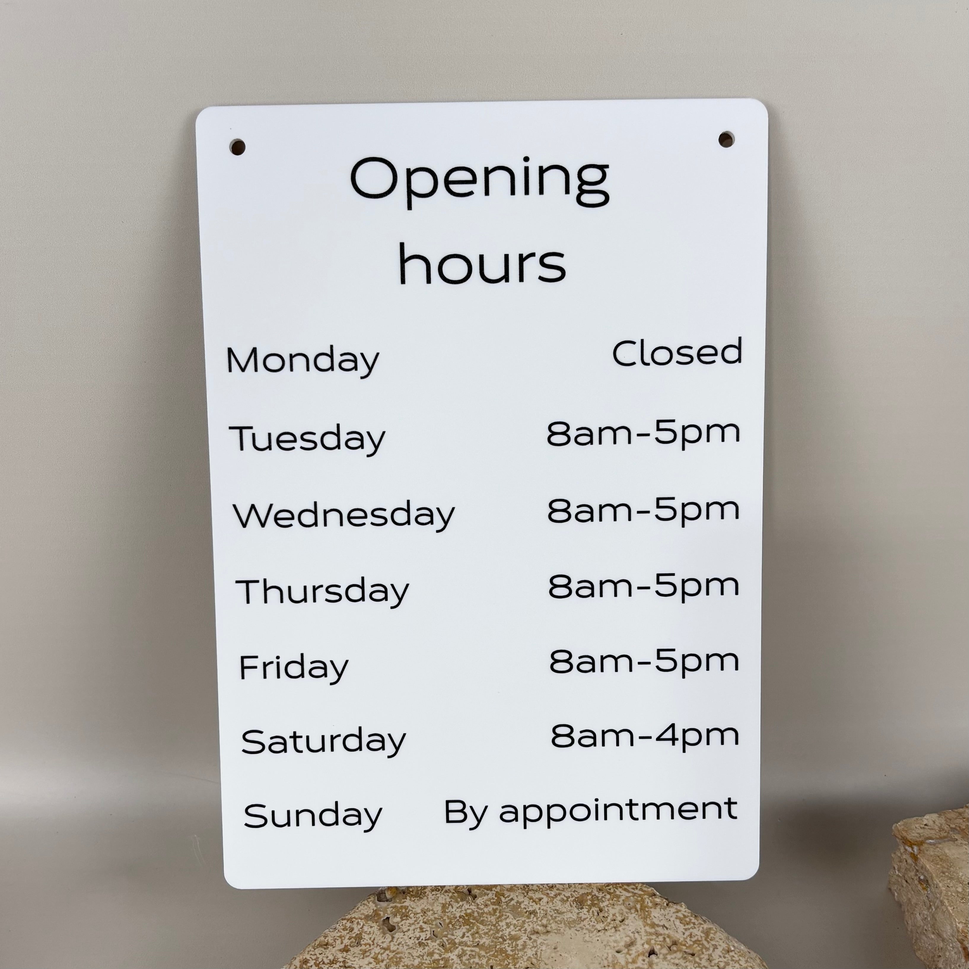 White acrylic opening hours sign with black text showing business hours Monday to Sunday wall mounted