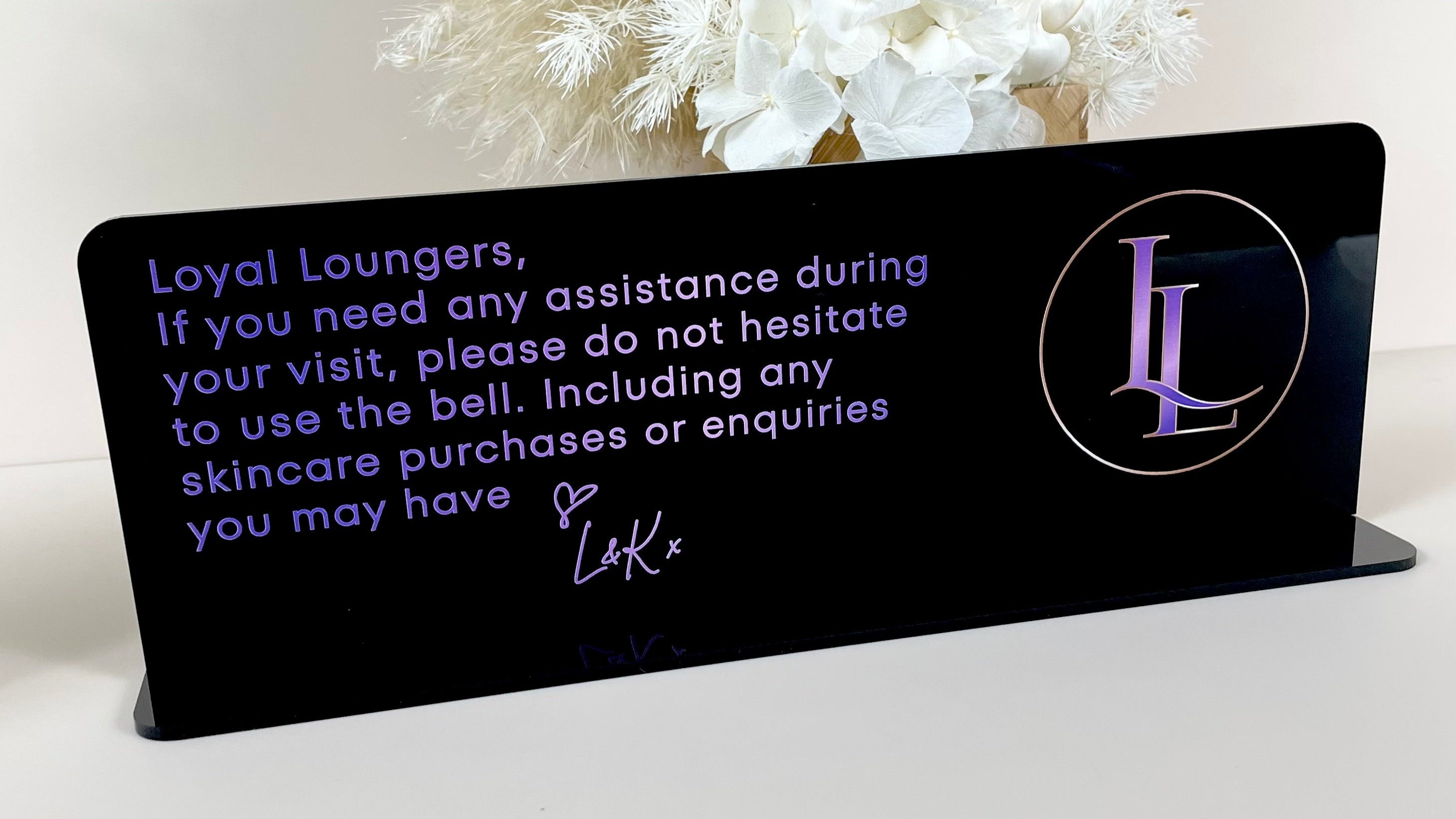 Custom signage with business message and floral styling for salon interior