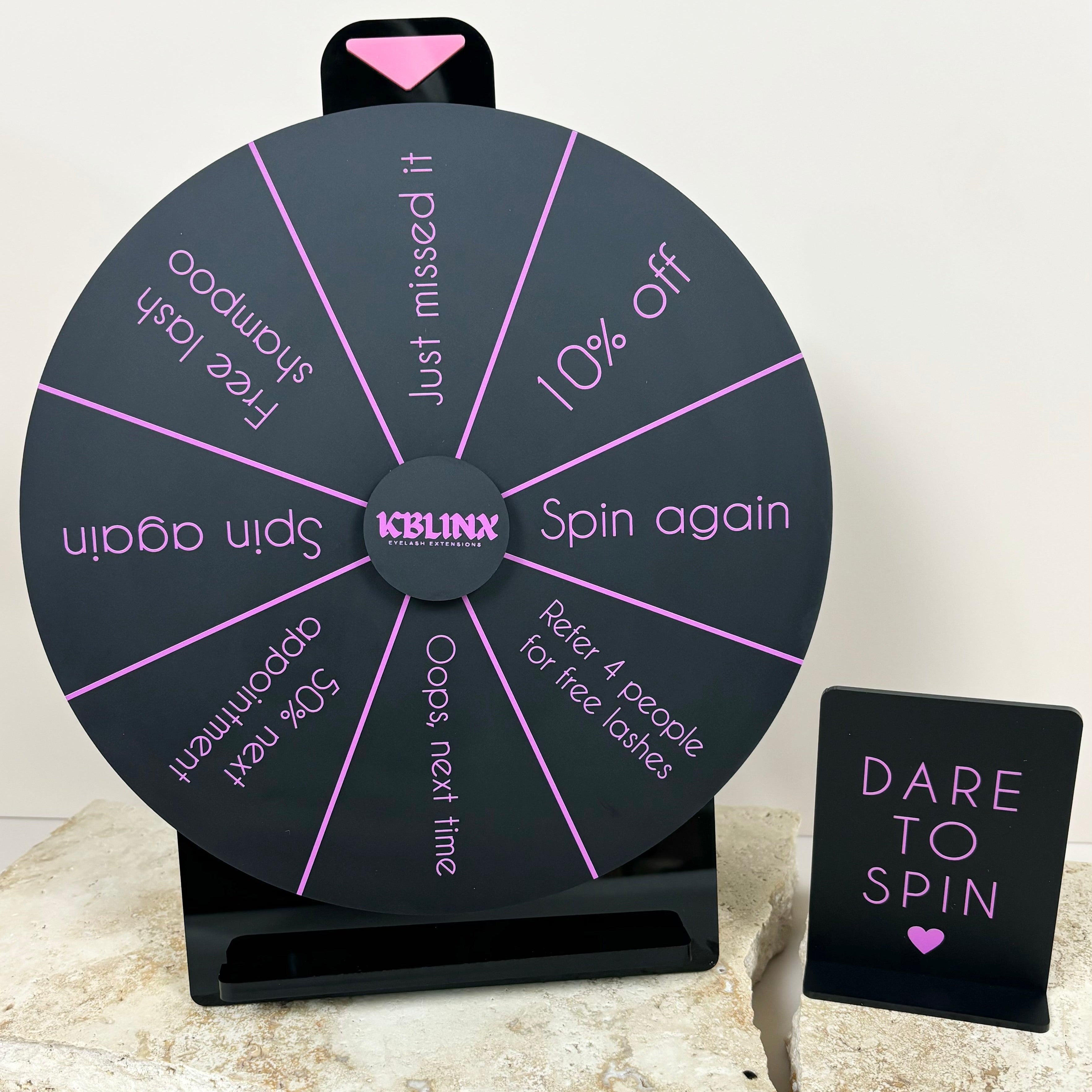 Black and pink prize wheel with branded sections for salons and shops