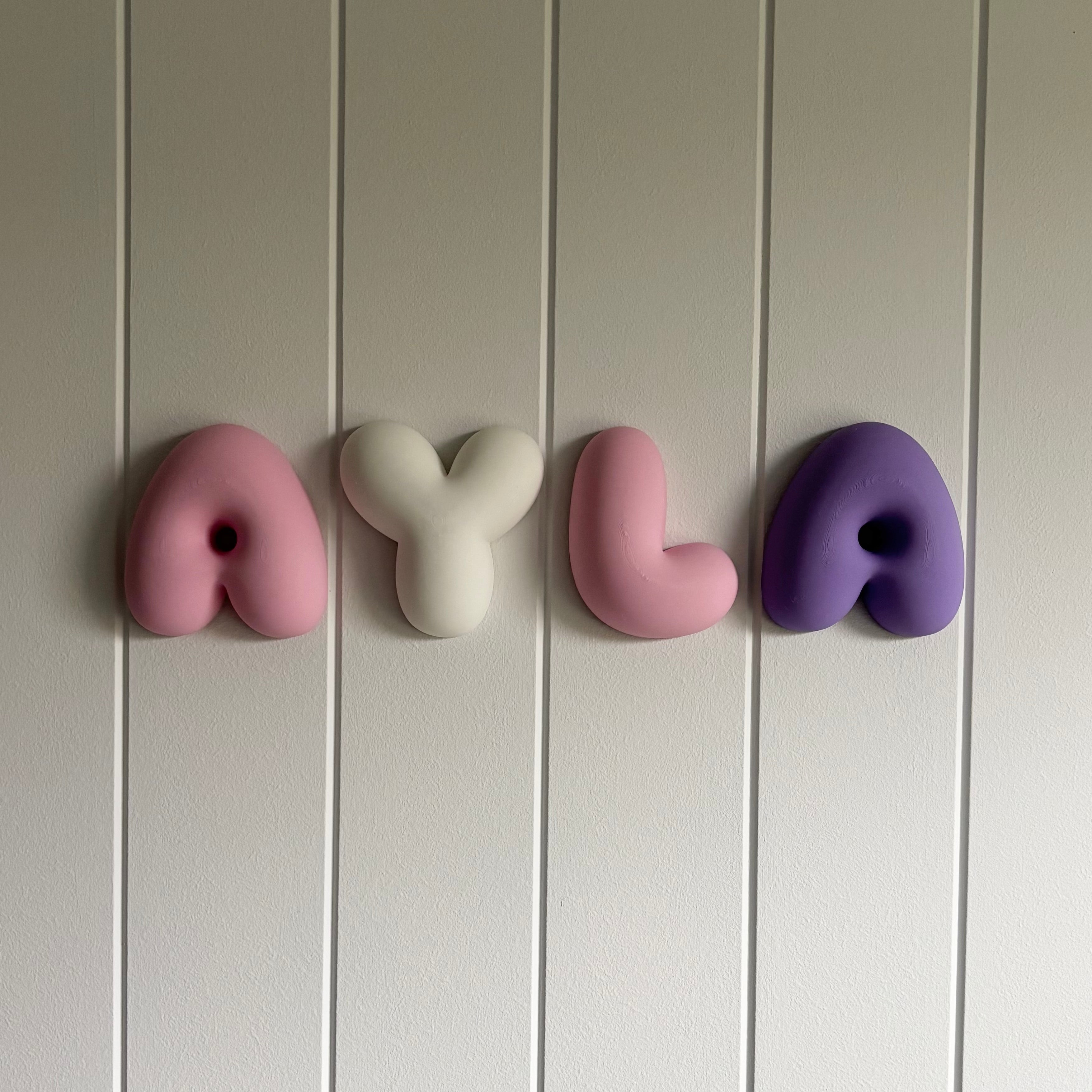 Custom 3D printed bubble name wall letters made from PLA, personalised nursery name sign in pastel pink, white and purple.