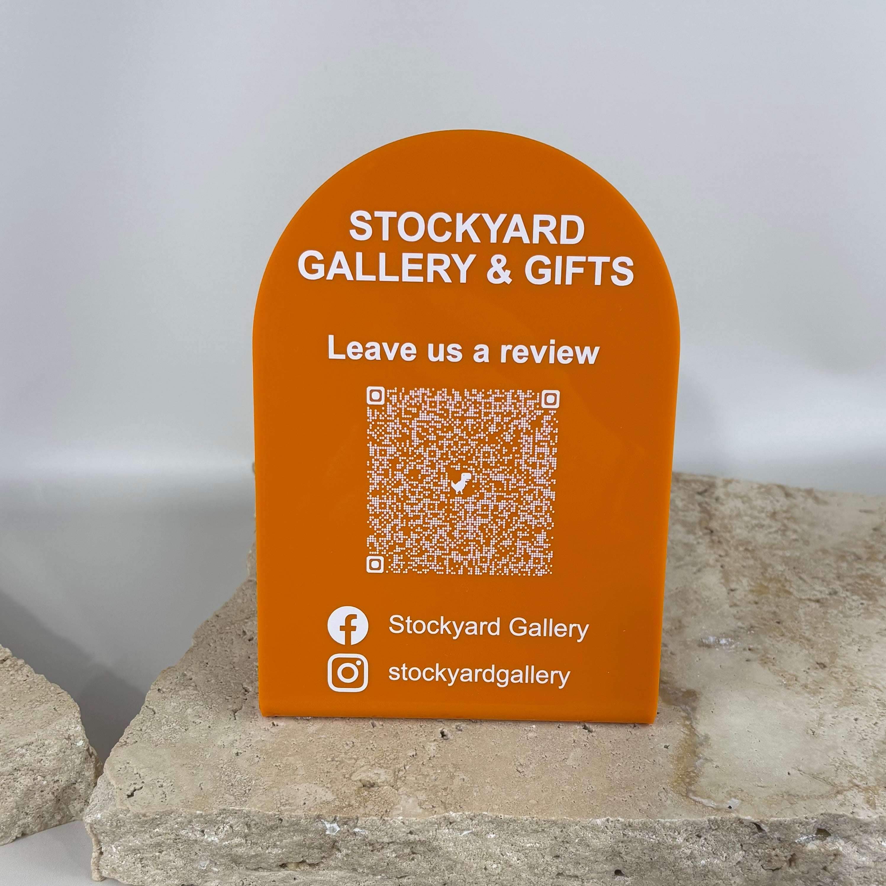 Custom curved acrylic QR review stand for shop counters featuring “Leave us a review” message, social media handles and branded business display signage.