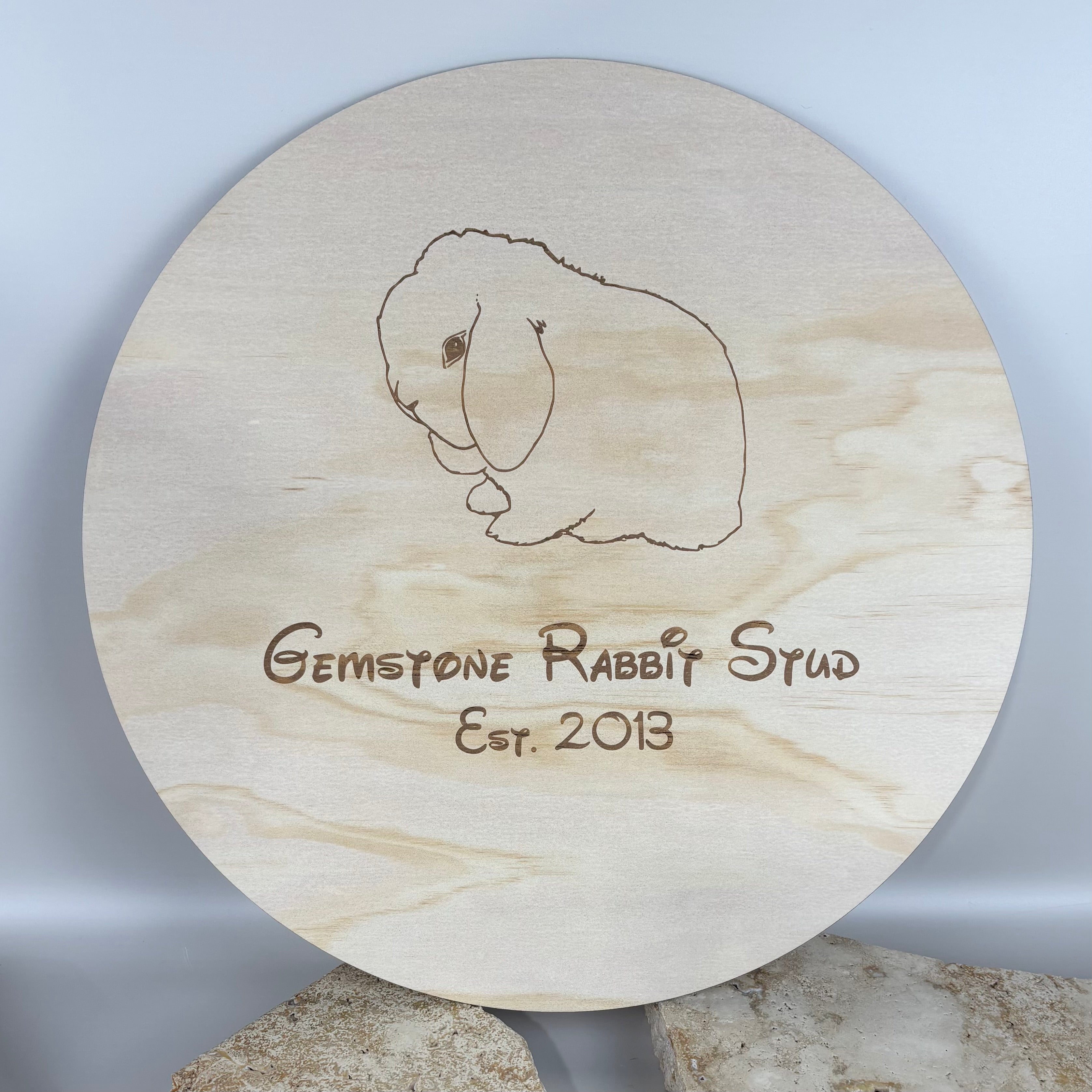 Round timber brand paddle engraved with rabbit illustration and “Gemstone Rabbit Stud Est. 2013” text, custom wooden paddle sign designed for rabbit breeders, small businesses and market displays.